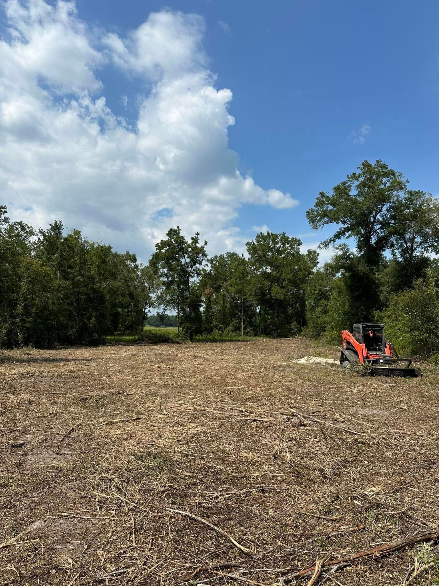 A tractor is driving through a field with trees in the background.