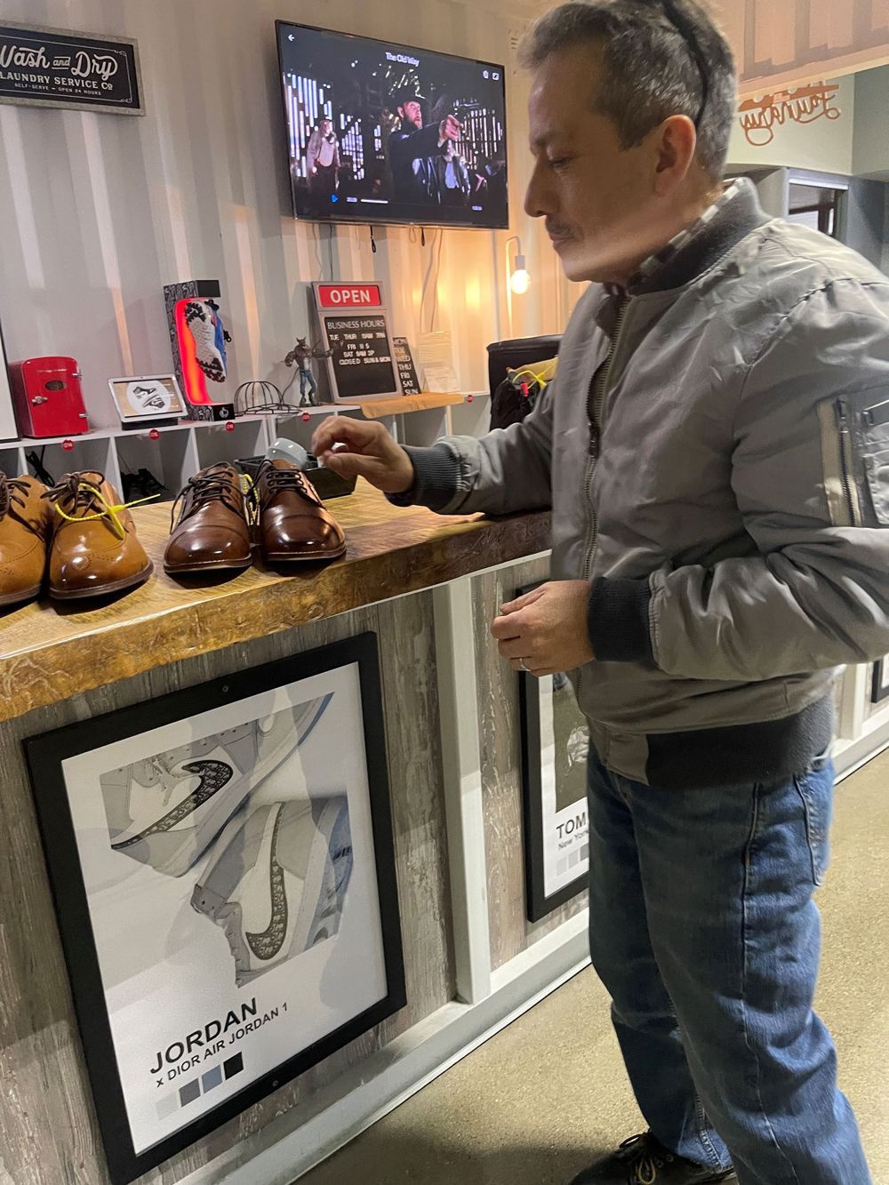 A man is standing in front of a counter in a store looking at shoes.