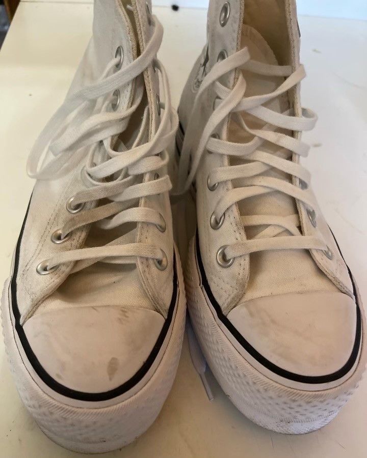 A pair of white high top sneakers with black laces