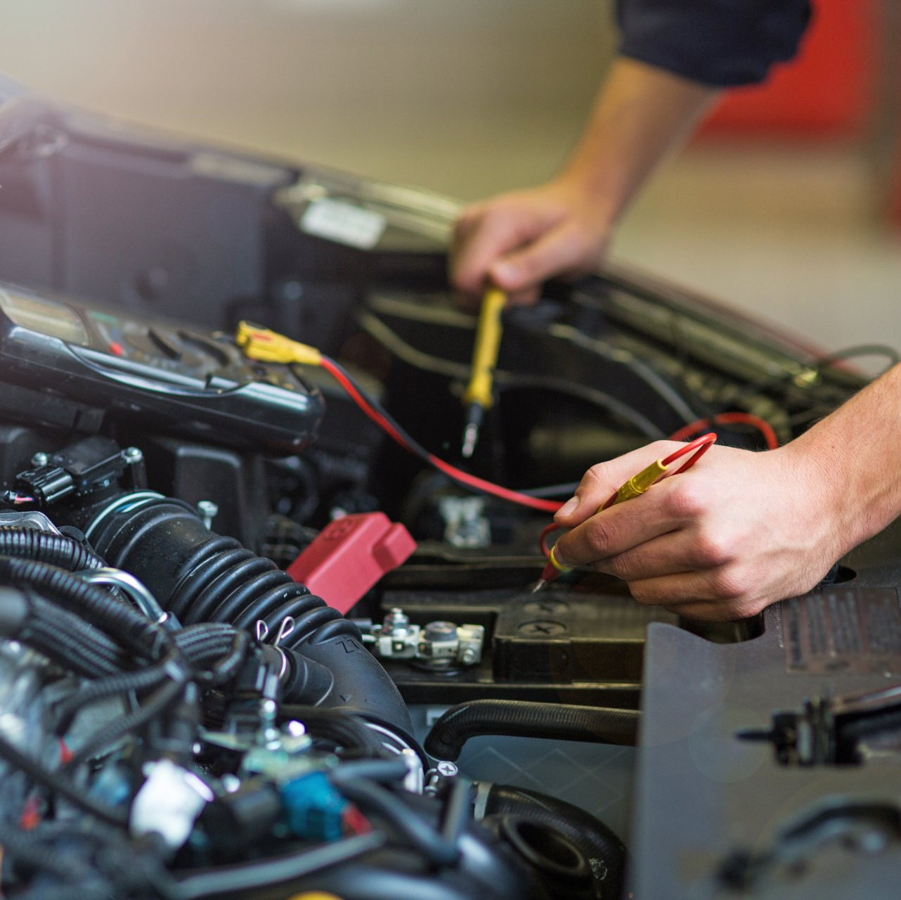 Eine Person arbeitet mit einem Schraubenzieher an einem Automotor.
