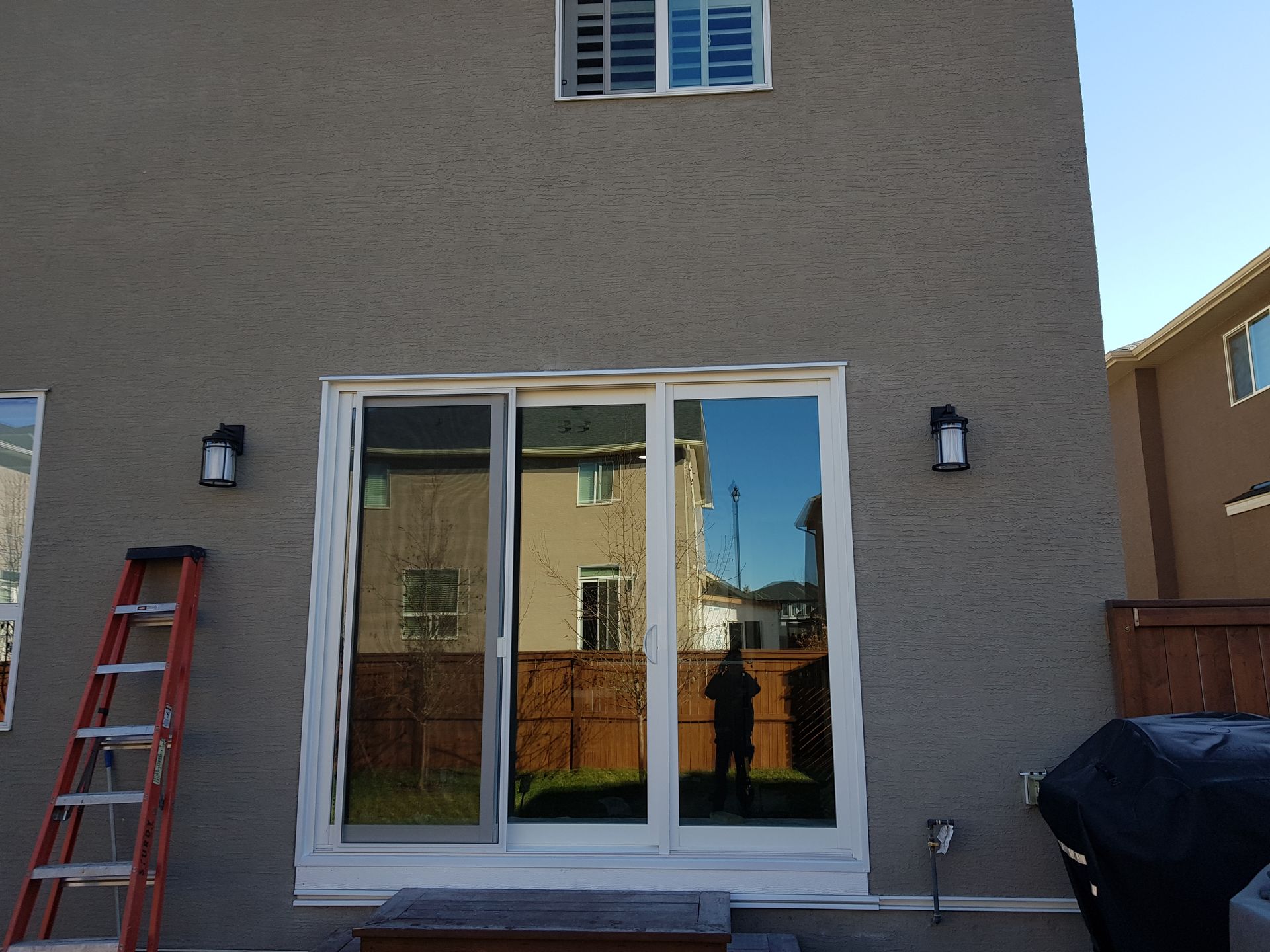 The back of a house with a ladder and sliding glass doors
