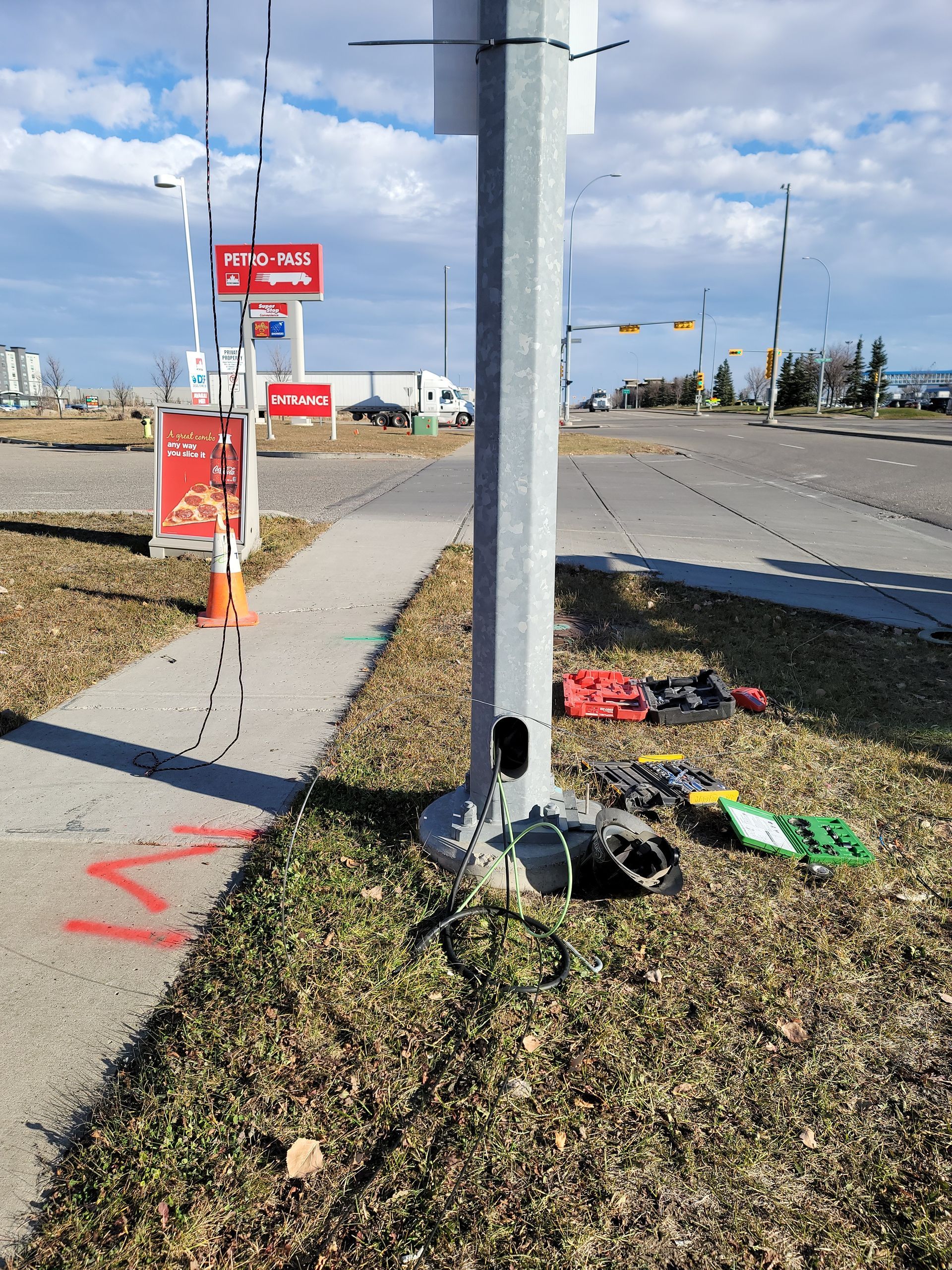 A pole with a hole in it is sitting on the side of the road.