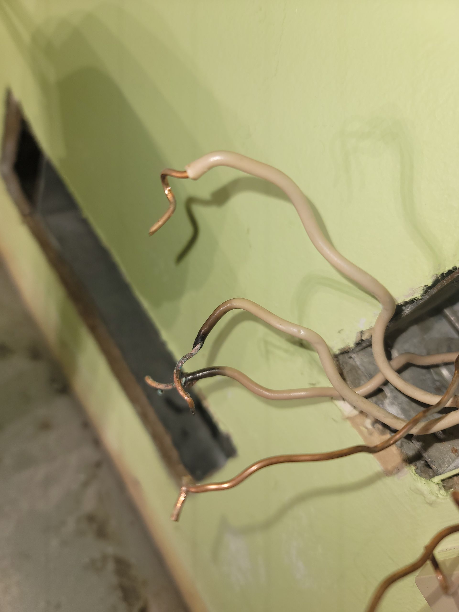 A bunch of wires sticking out of a hole in a wall