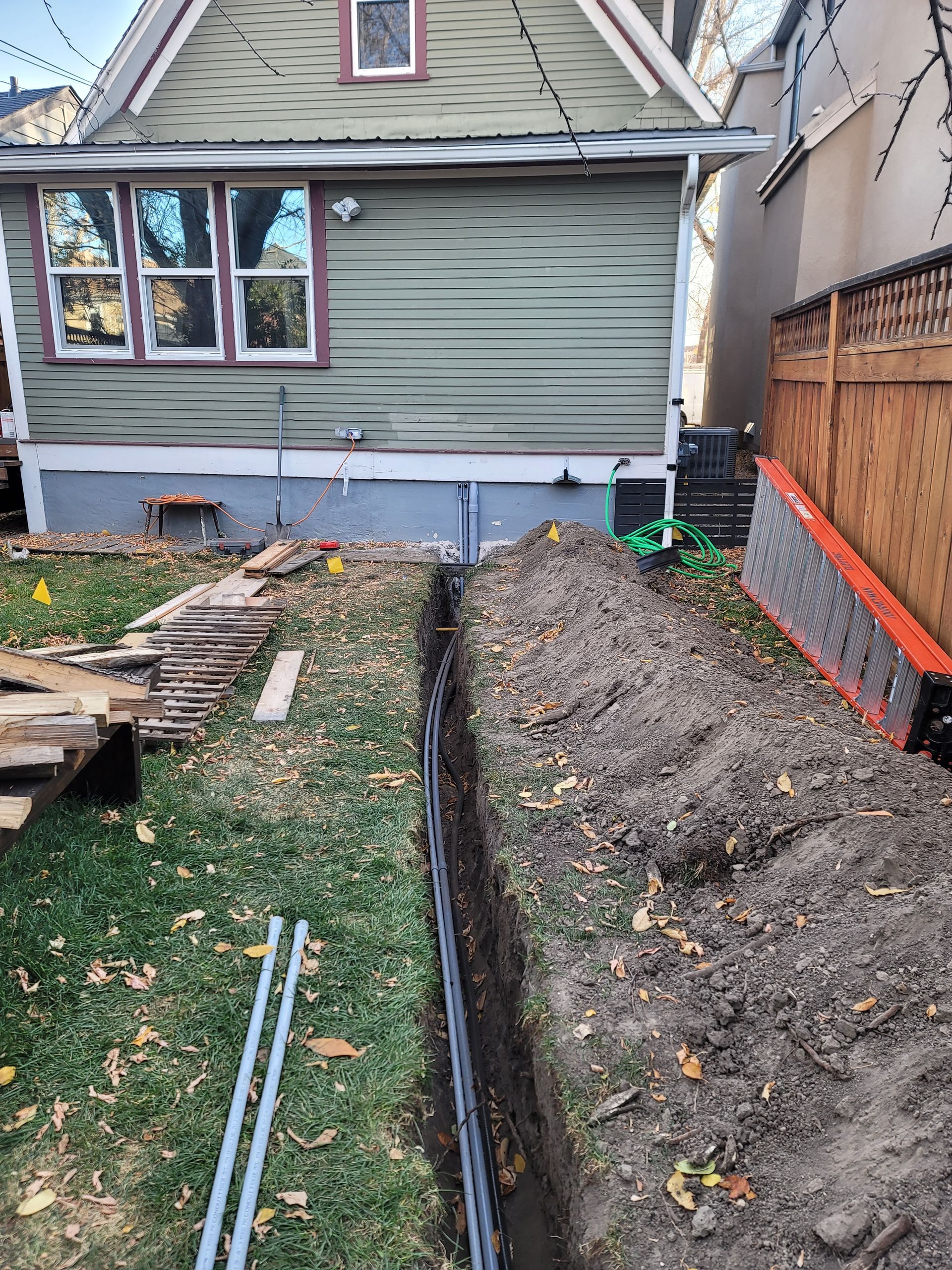 A house is being remodeled and a trench is being dug in front of it.