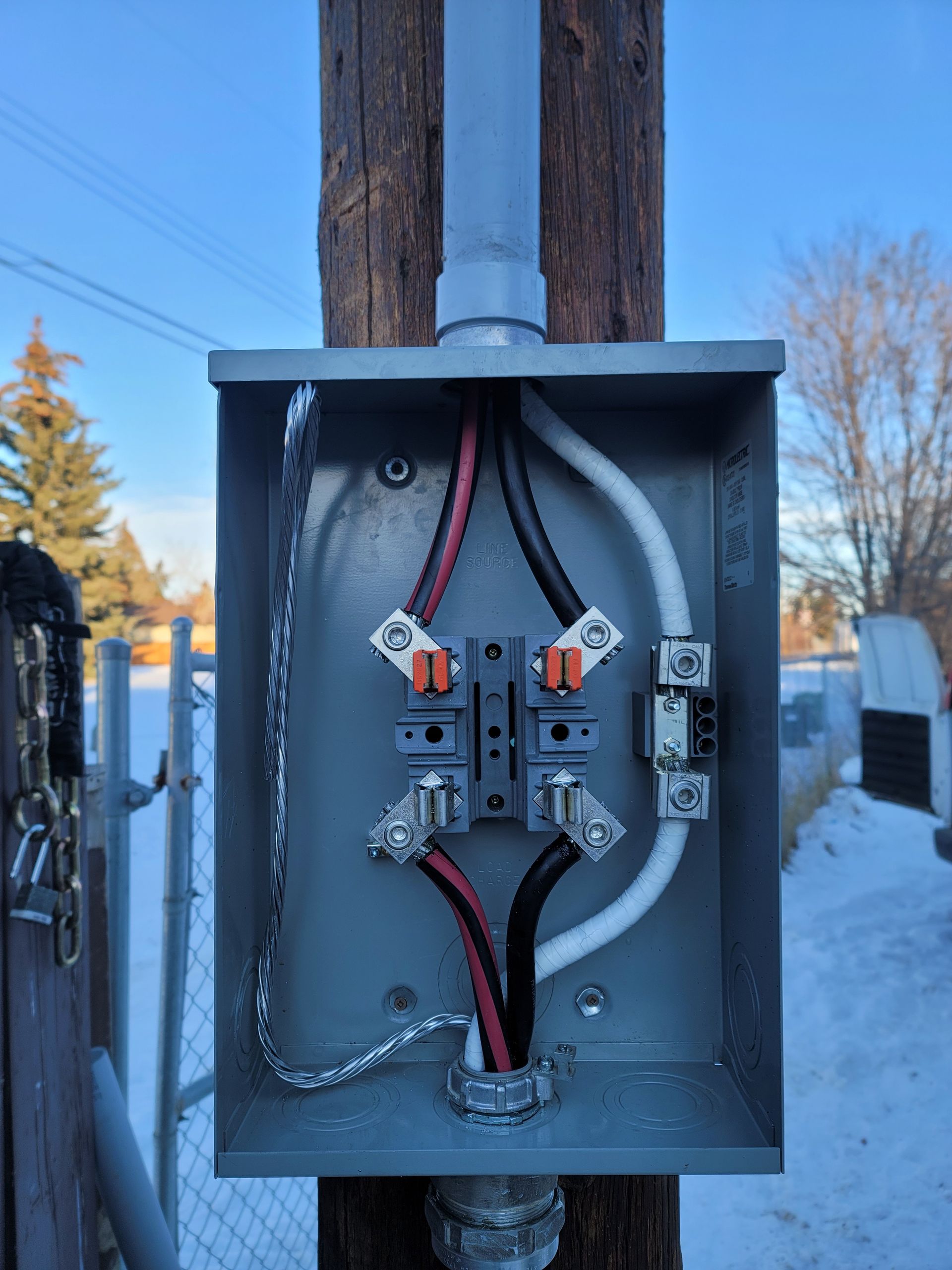 A box with wires coming out of it is attached to a pole.
