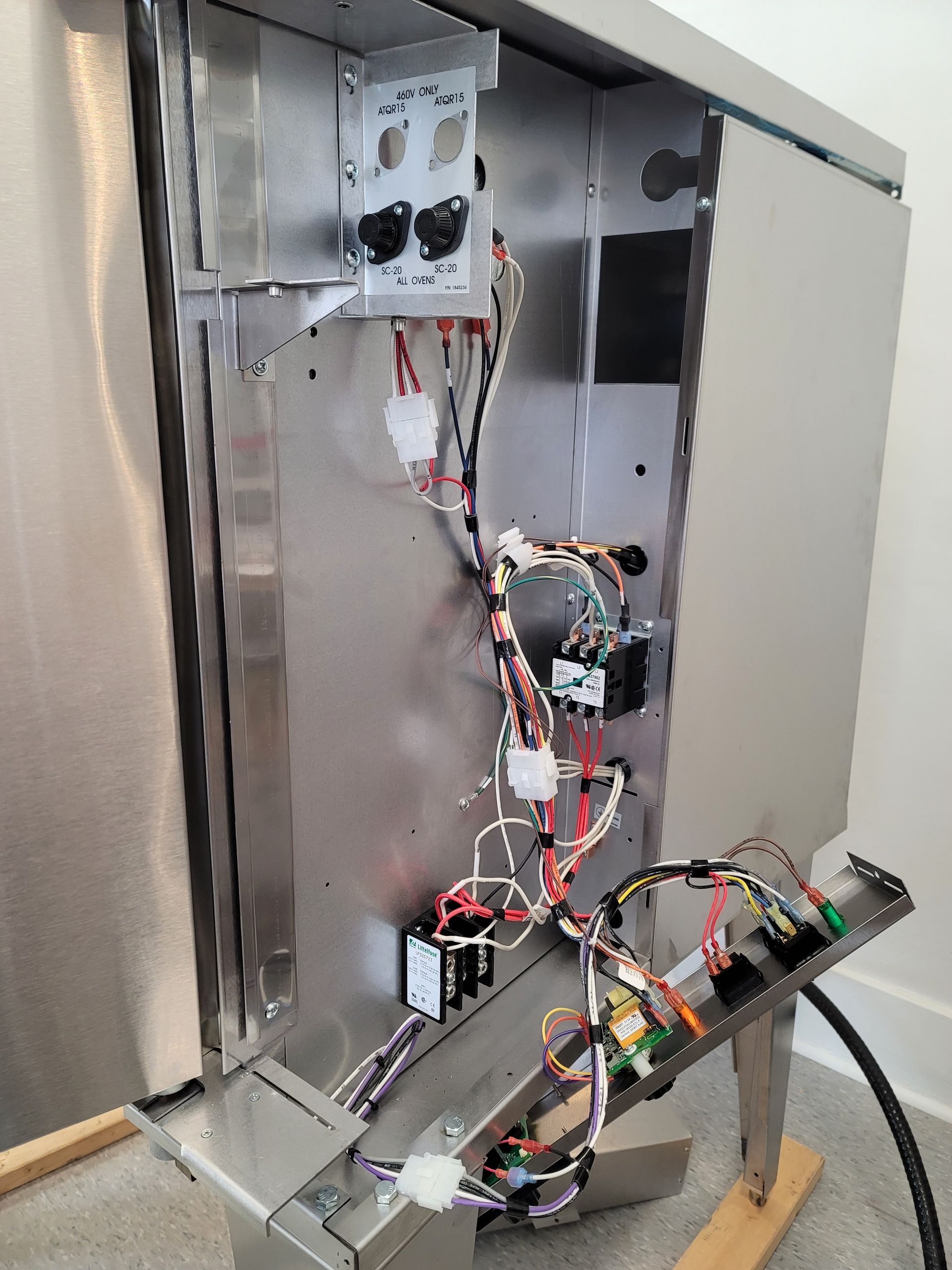 The inside of a stainless steel refrigerator with a lot of wires coming out of it.