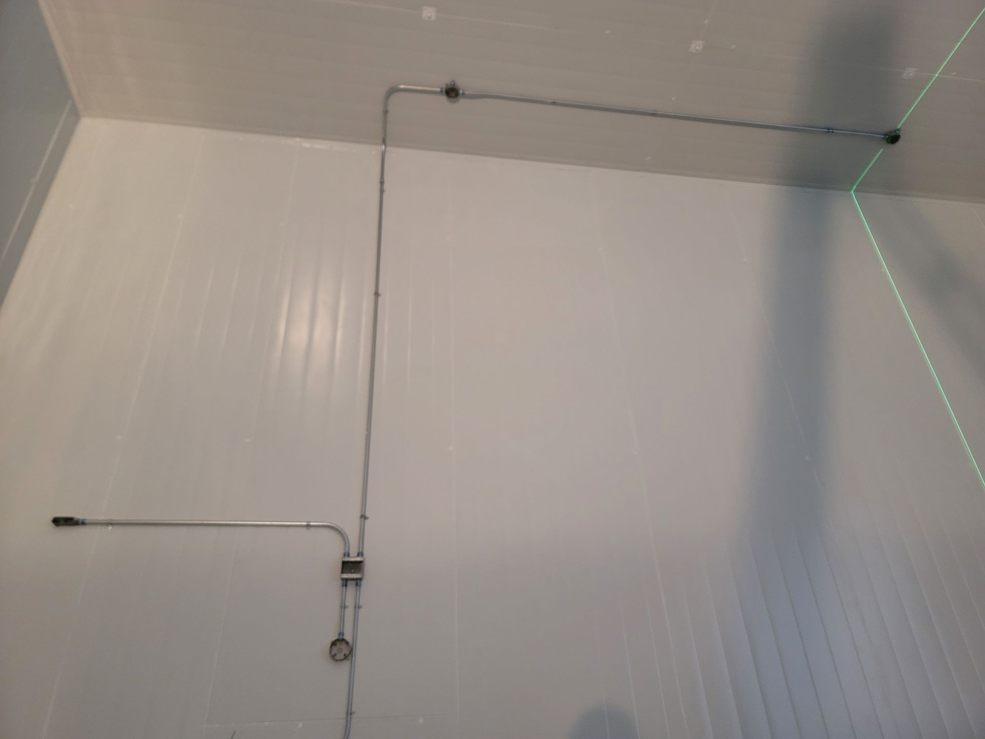 A room with white walls and pipes hanging from the ceiling.