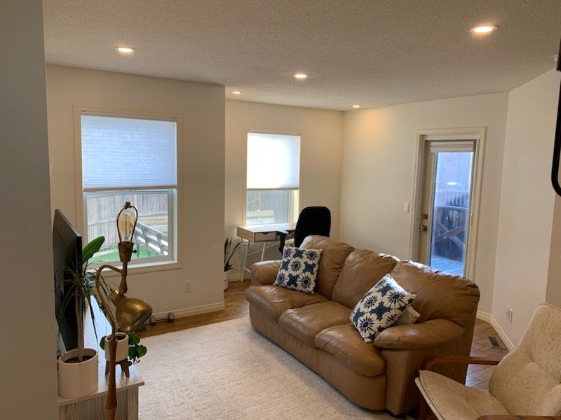 A living room with a couch , chair , lamp and window.