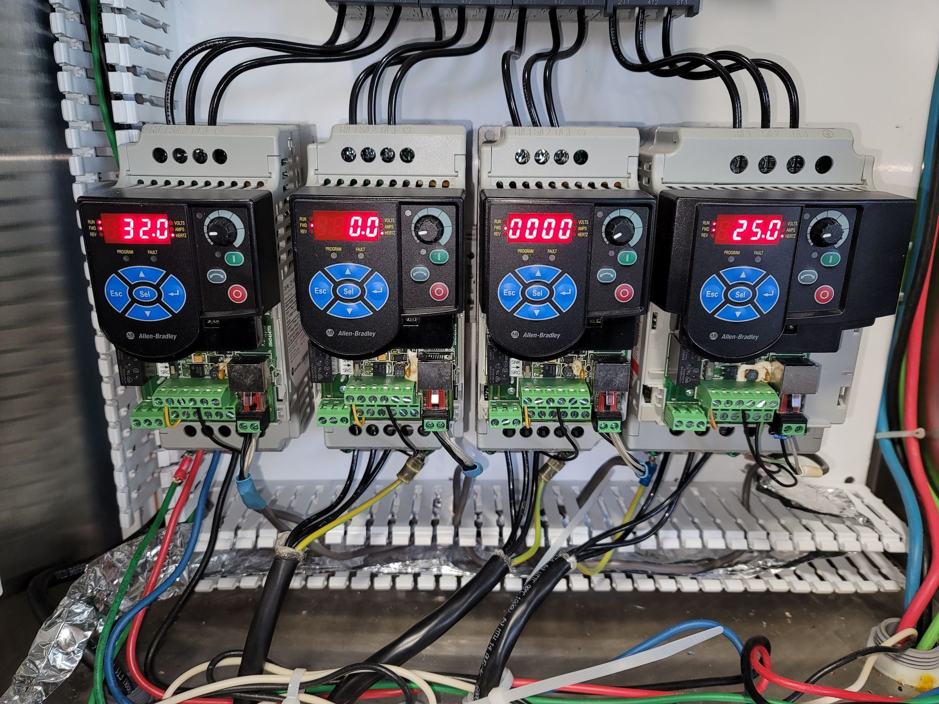 Four electrical motor drives in a panel, each displaying speed on red screens.