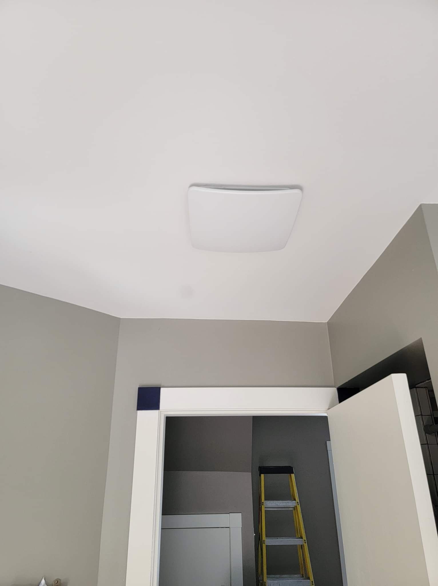 A room with a ladder and a light on the ceiling.