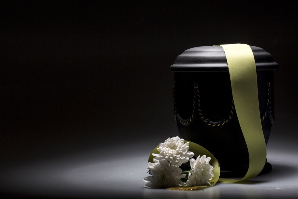 Black Urn With A Yellow Ribbon And White Flowers On A Table — Northern Rivers Headstones in Casino, NSW