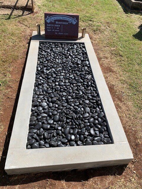 A Grave In A Cemetery With Black Rocks In It — Northern Rivers Headstones in Casino NSW