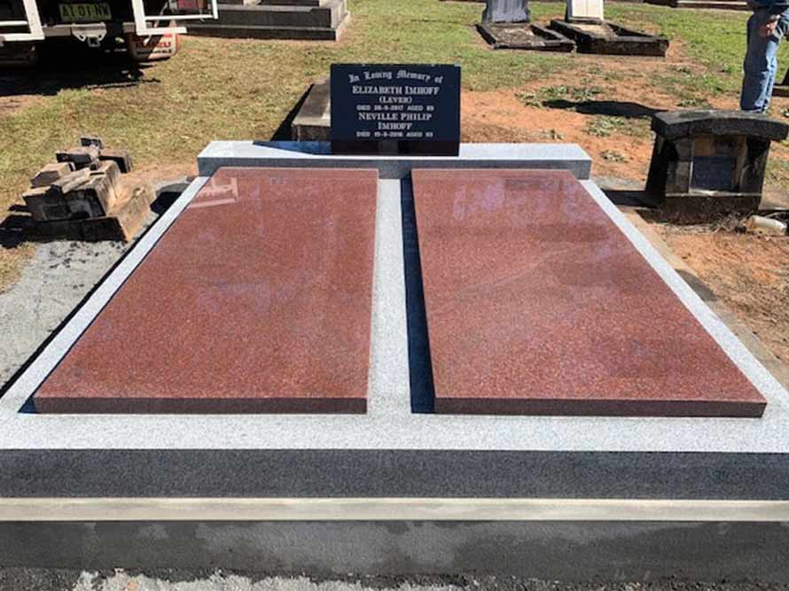 A Grave In A Cemetery With Two Red Slabs And A Black Gravestone — Northern Rivers Headstones in Casino NSW