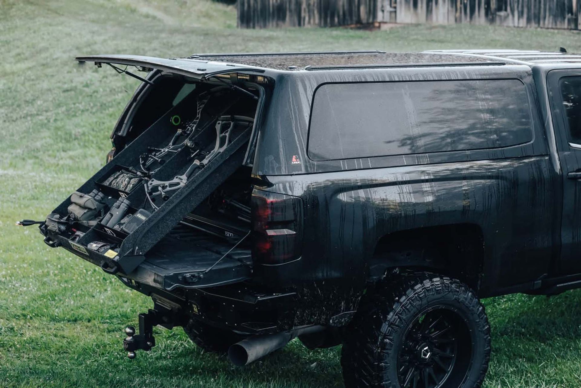 Black truck with bed open, holding a gun safe outdoors on green grass.