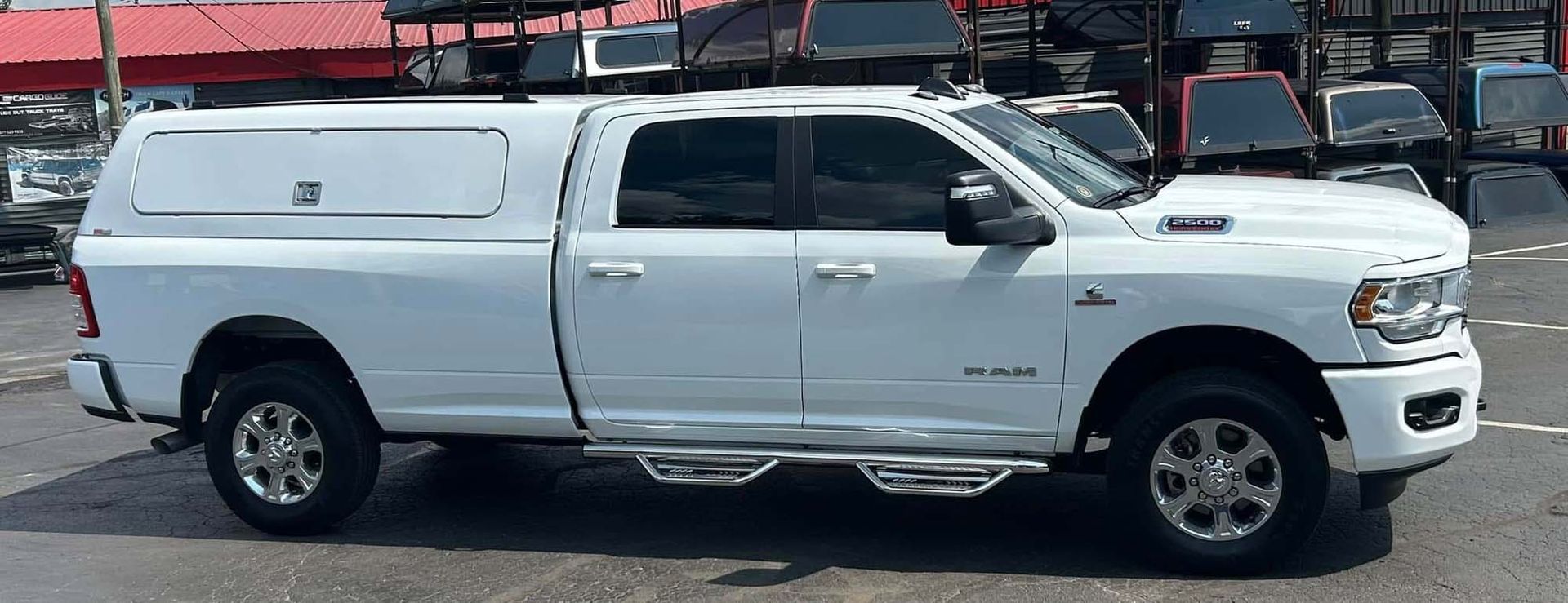 White pickup truck with a matching camper shell parked outside.
