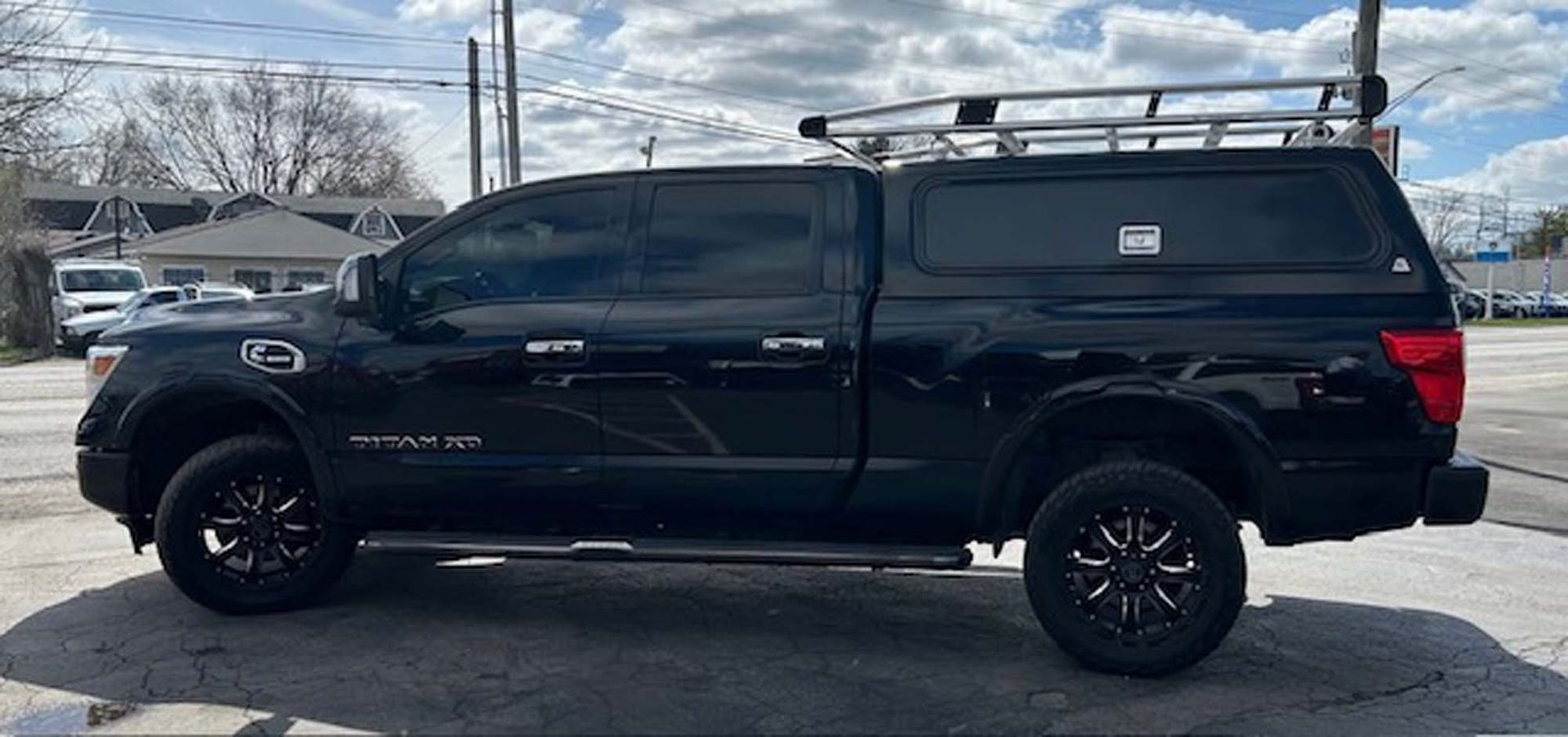 Black Nissan Titan truck with a truck bed cap and roof rack, parked outside.