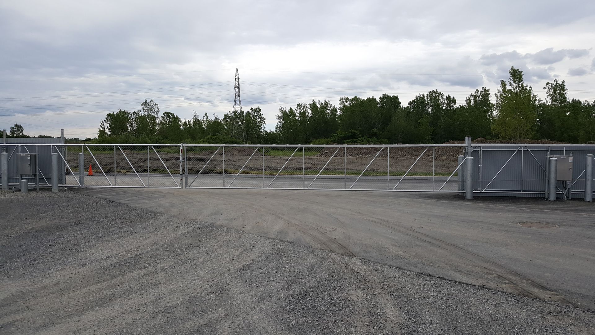 Une grande porte en métal se trouve au milieu d'un chemin de gravier.