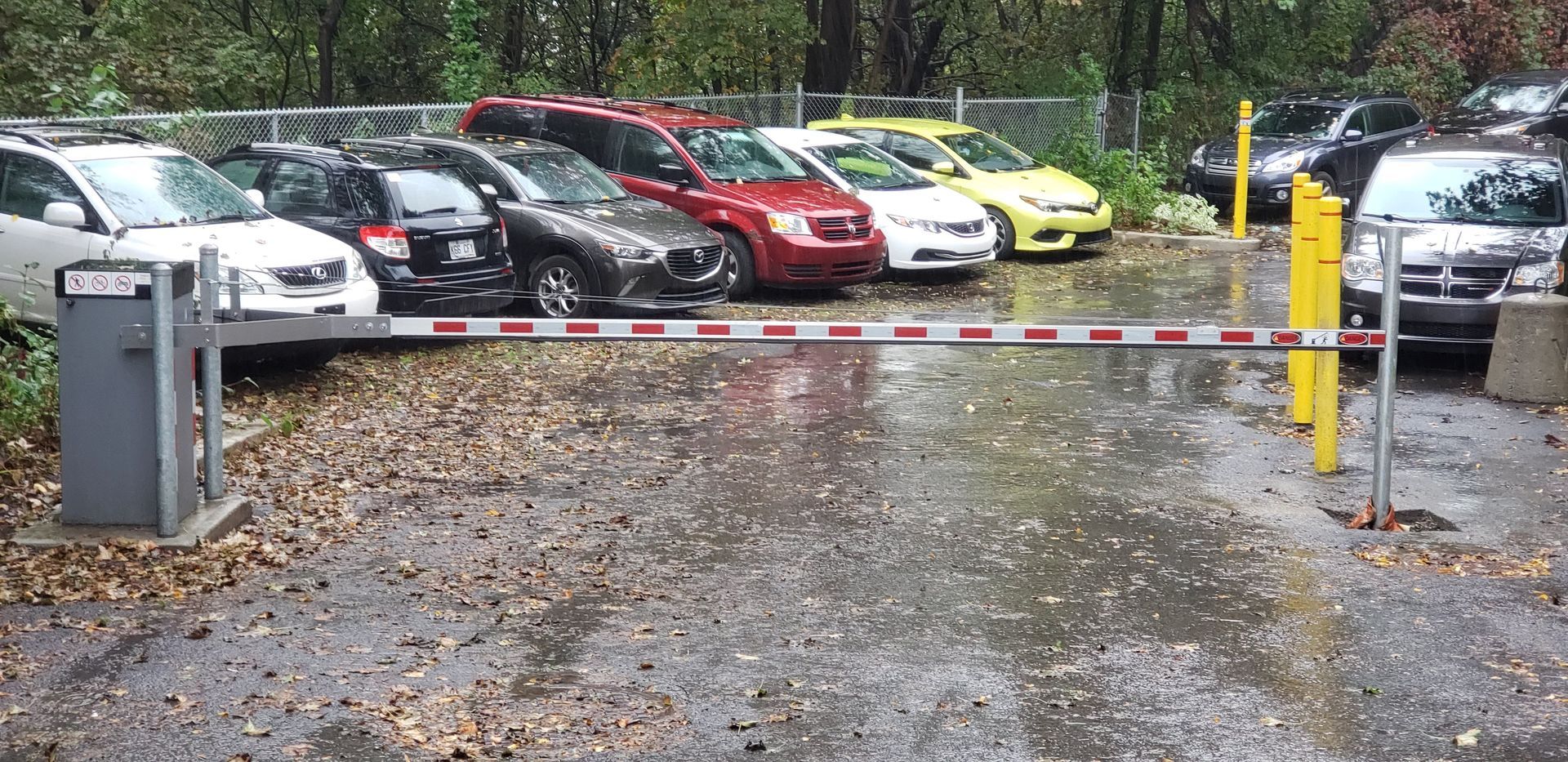 Un parking avec des voitures garées derrière une barrière