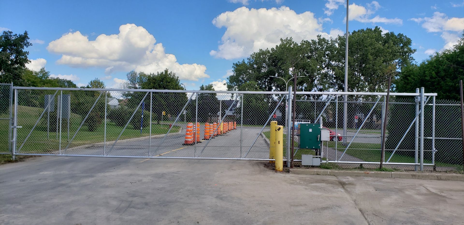 Un parking vide avec une clôture grillagée et un portail.