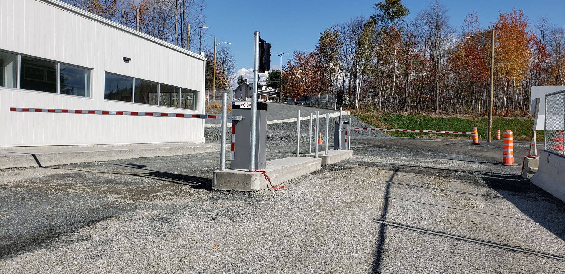 Un parking avec une barrière et un bâtiment blanc en arrière-plan.