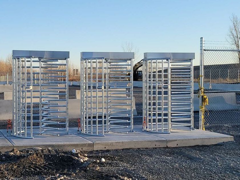 Une rangée de tourniquets est alignée dans une zone de gravier.