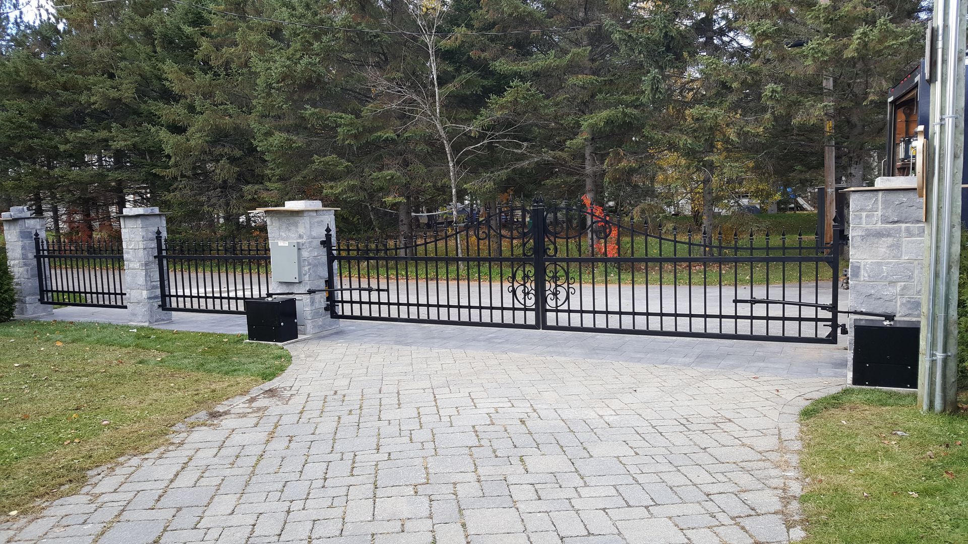 Un portail noir est ouvert sur une allée en briques.