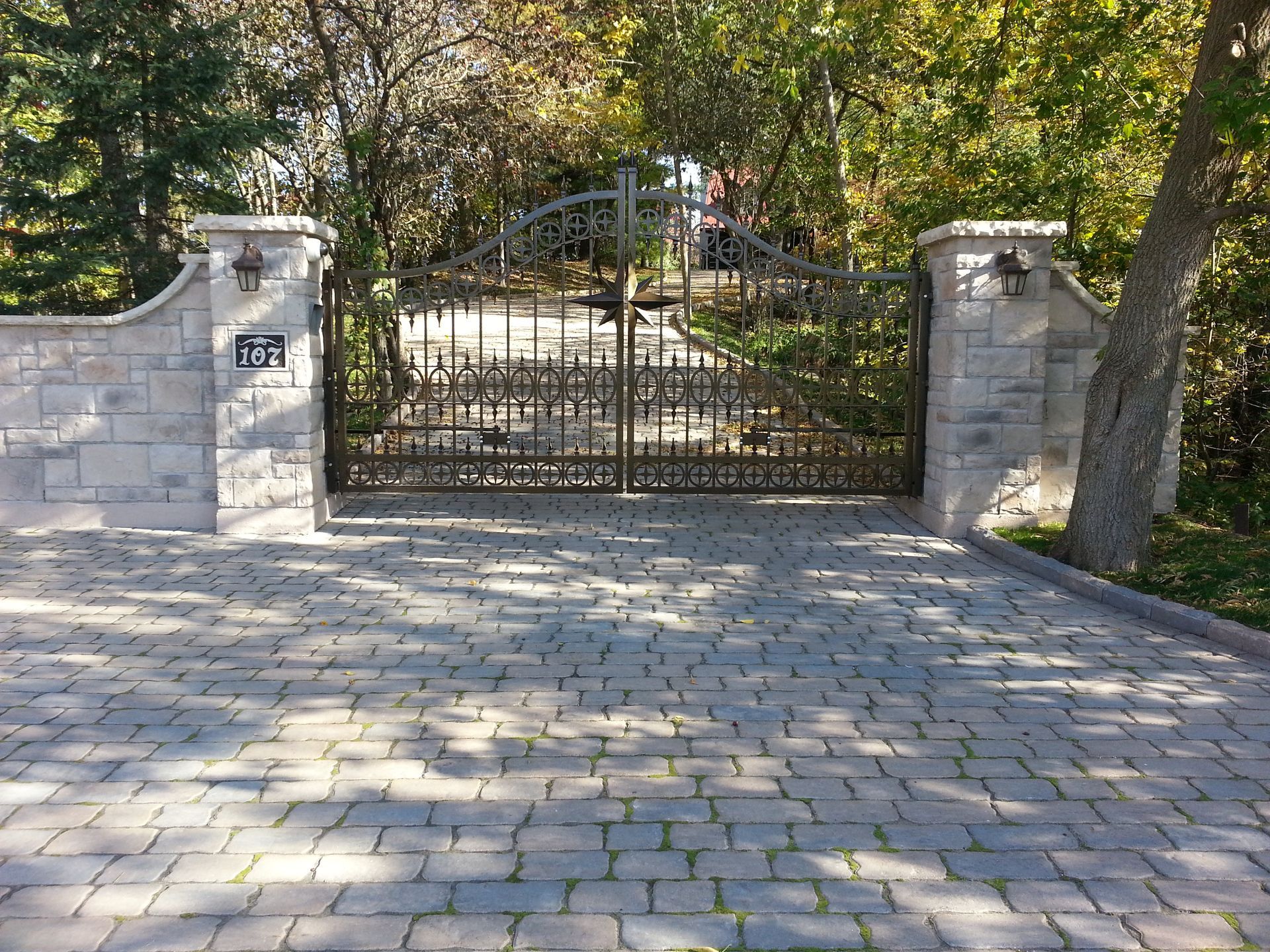 Une allée en briques avec un portail en fer forgé menant à une maison.