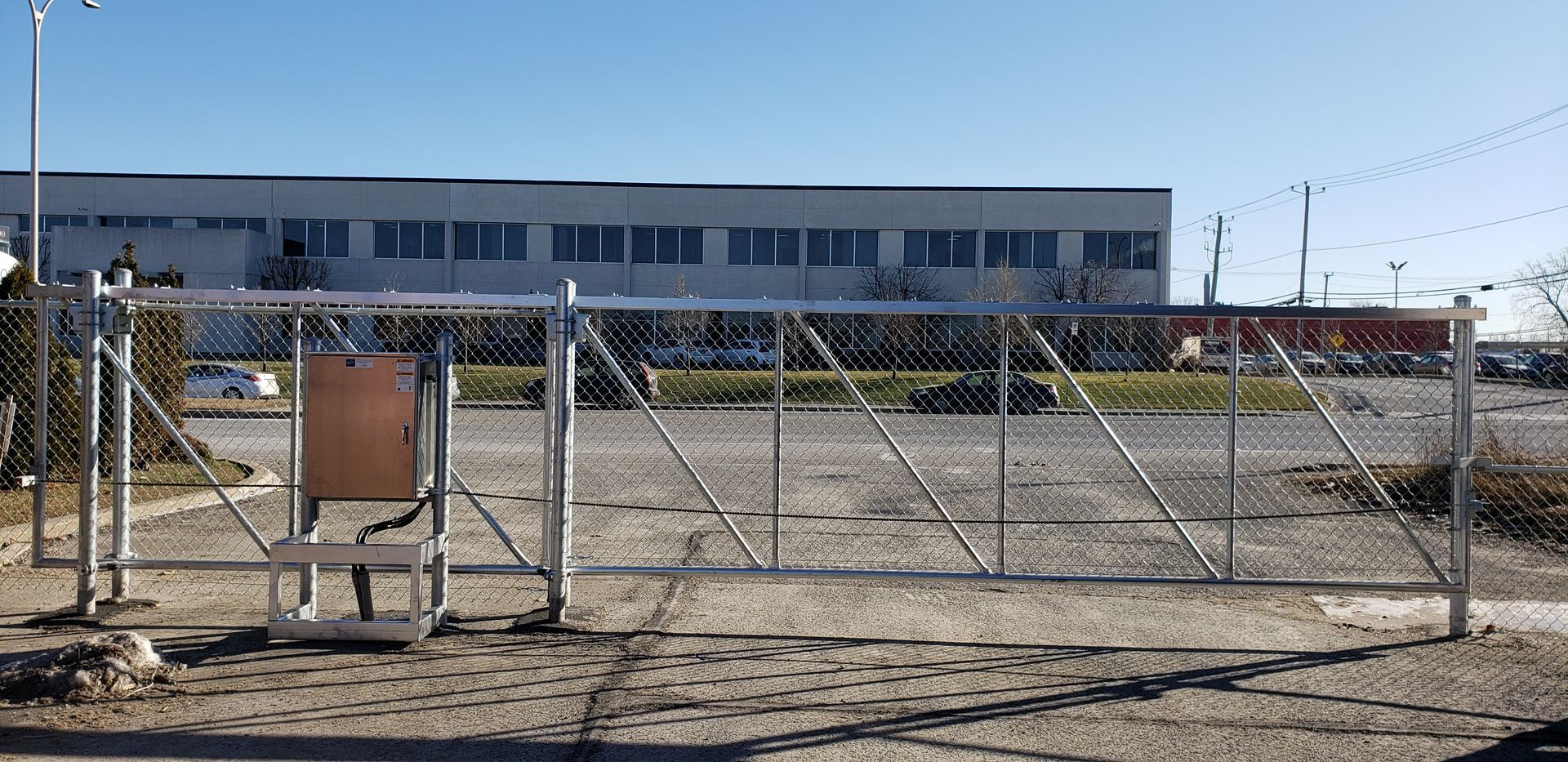 Une clôture grillagée avec un portail devant un bâtiment
