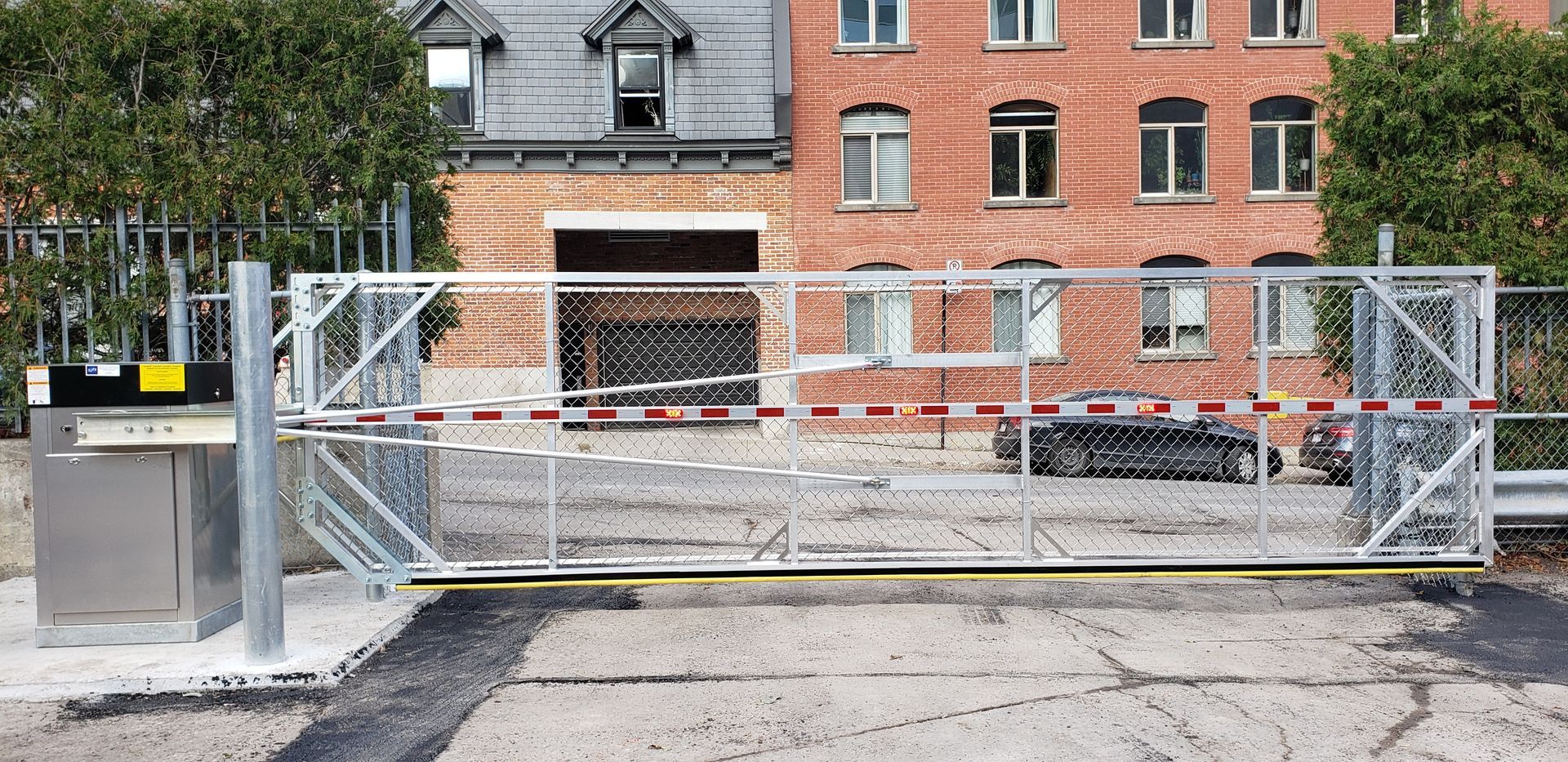 Un portail coulissant est fermé devant un bâtiment en briques.