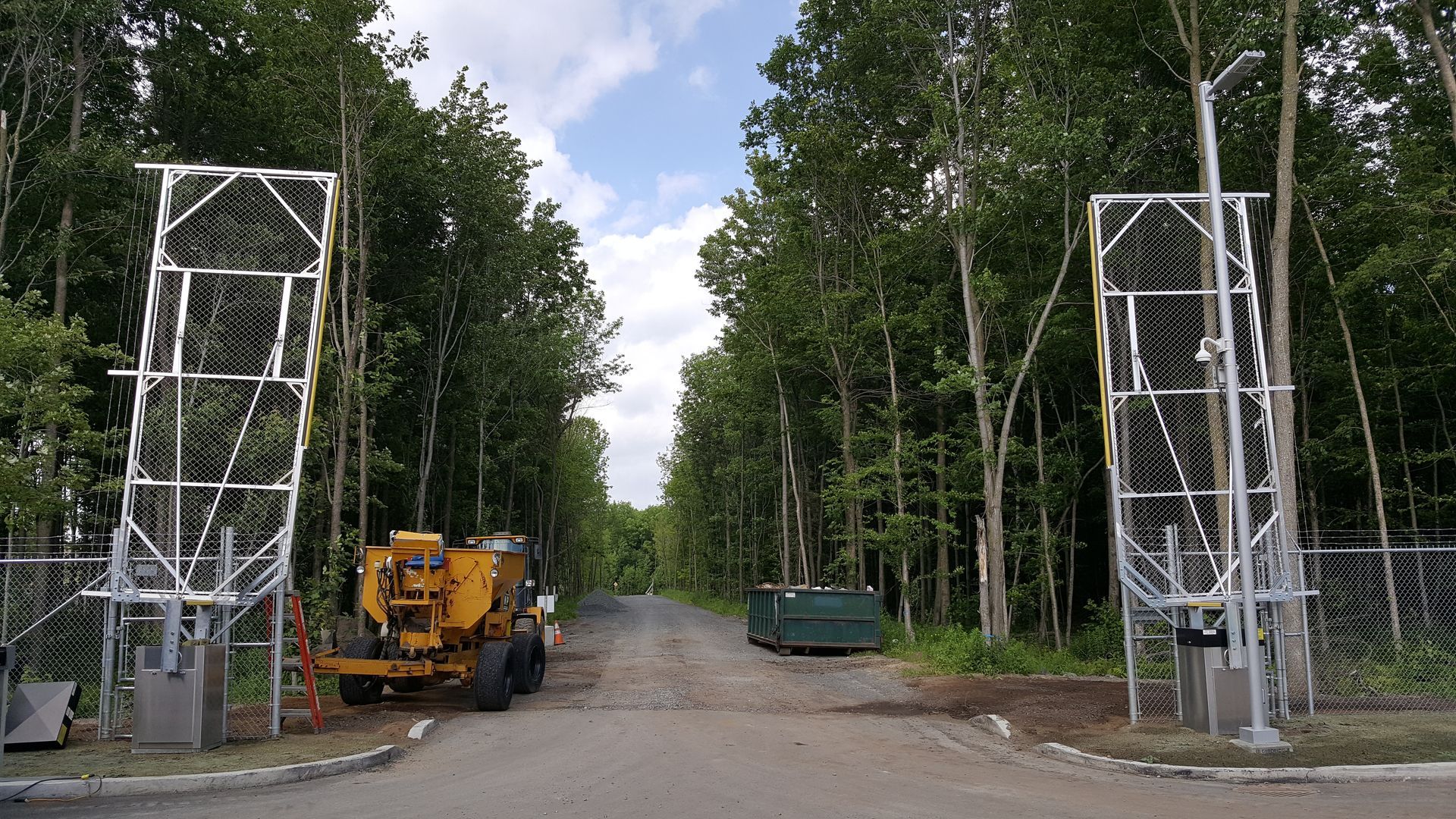 Un camion jaune est garé au milieu d'une route entourée d'arbres.