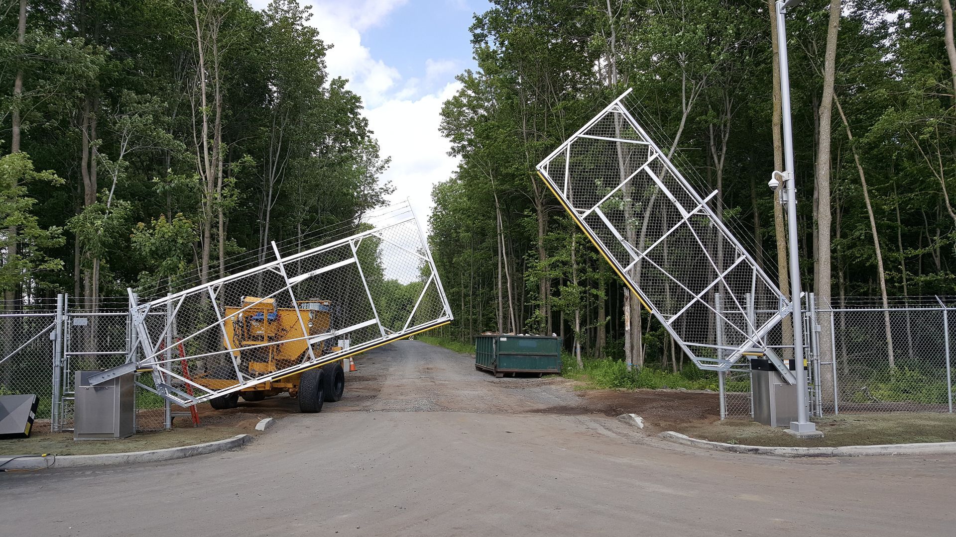 Une grande structure métallique est posée sur le bord d'une route à côté d'une clôture.