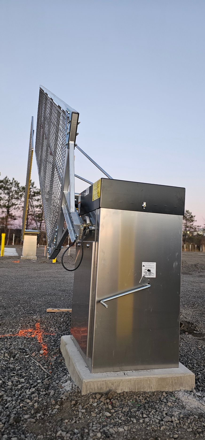 Une boîte en acier inoxydable se trouve au milieu d'un champ de gravier.
