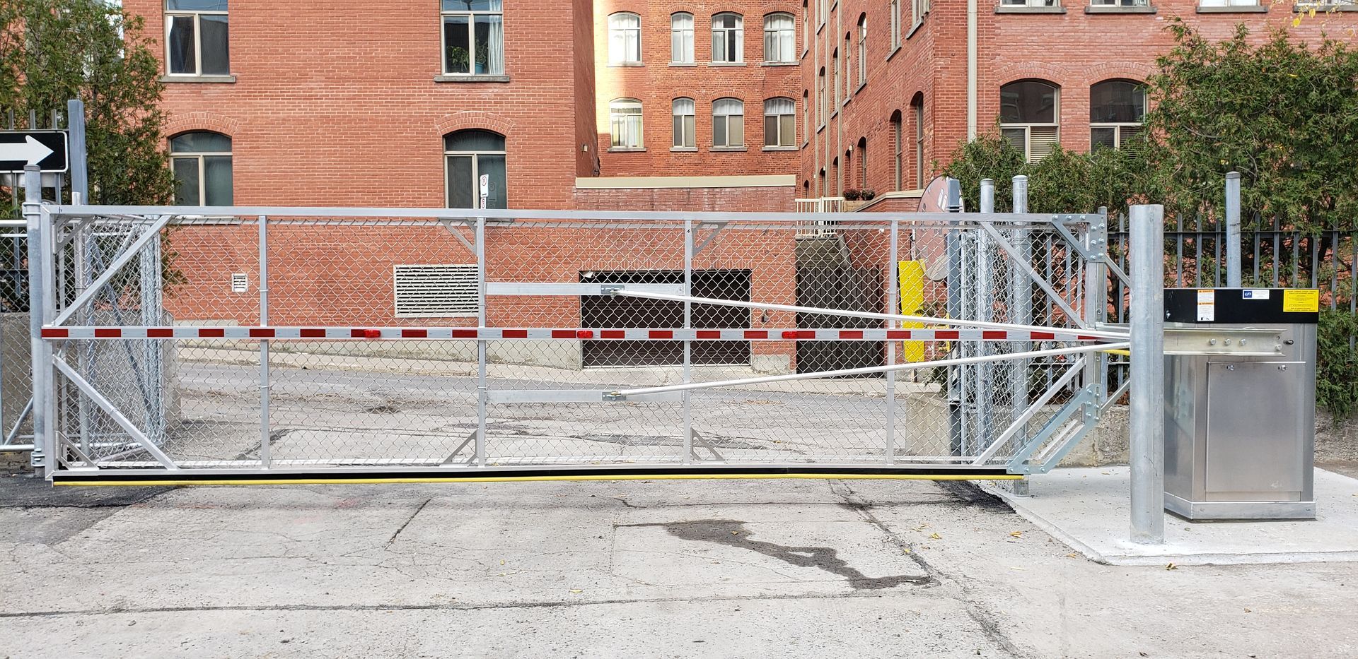 Une grande porte en métal se trouve devant un bâtiment en briques.