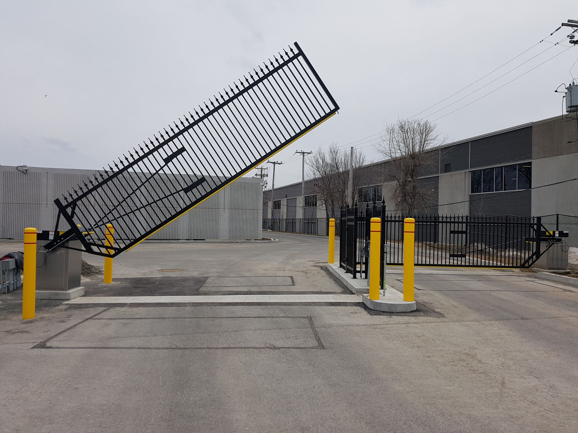 Une clôture avec un poteau jaune devant un bâtiment
