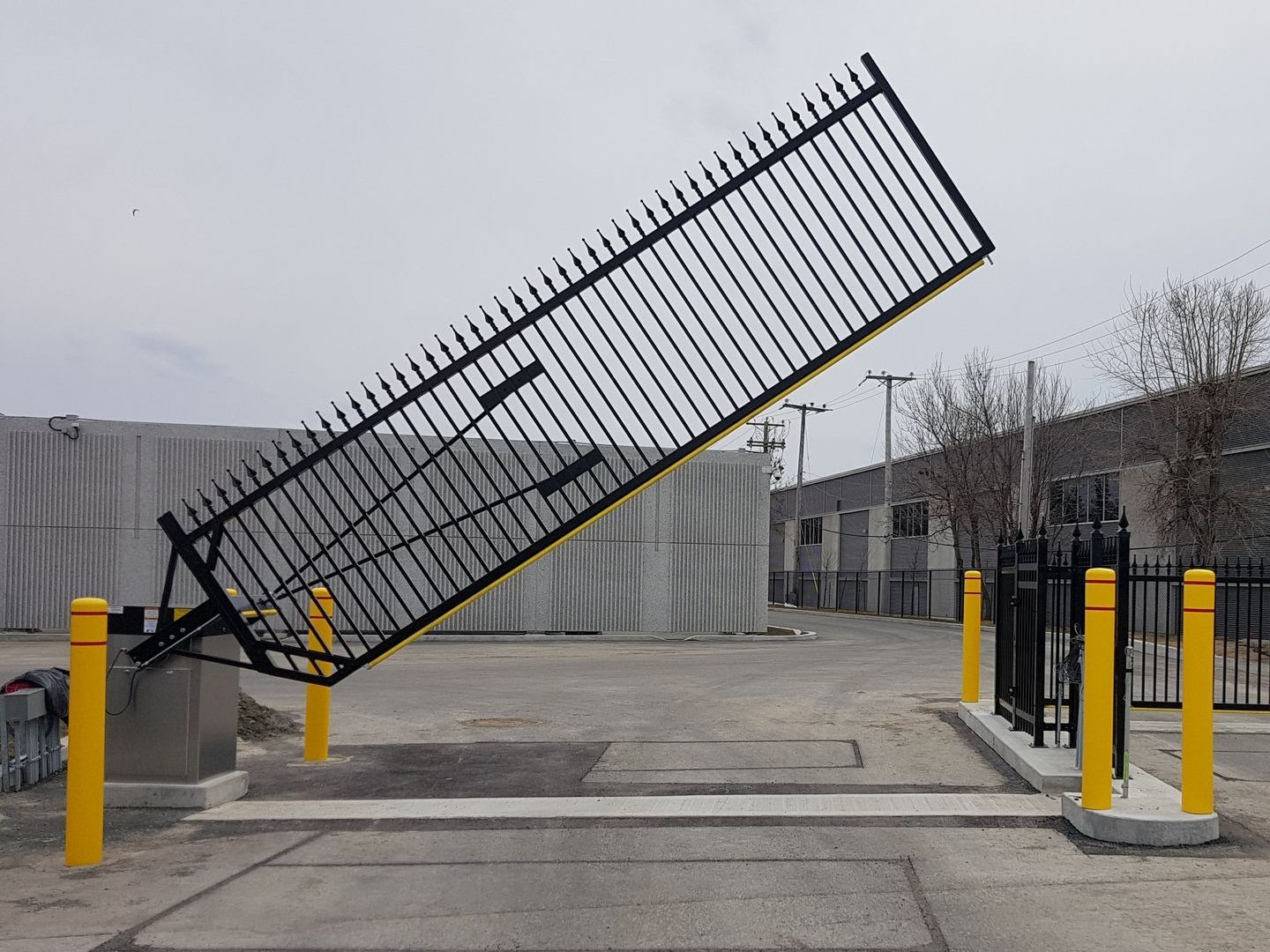 Une clôture noire avec un poteau jaune devant