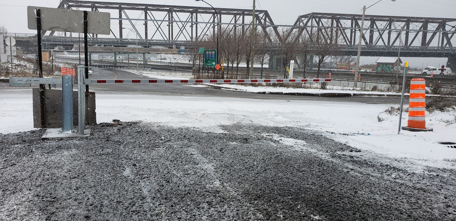 Une route enneigée avec un pont en arrière-plan.