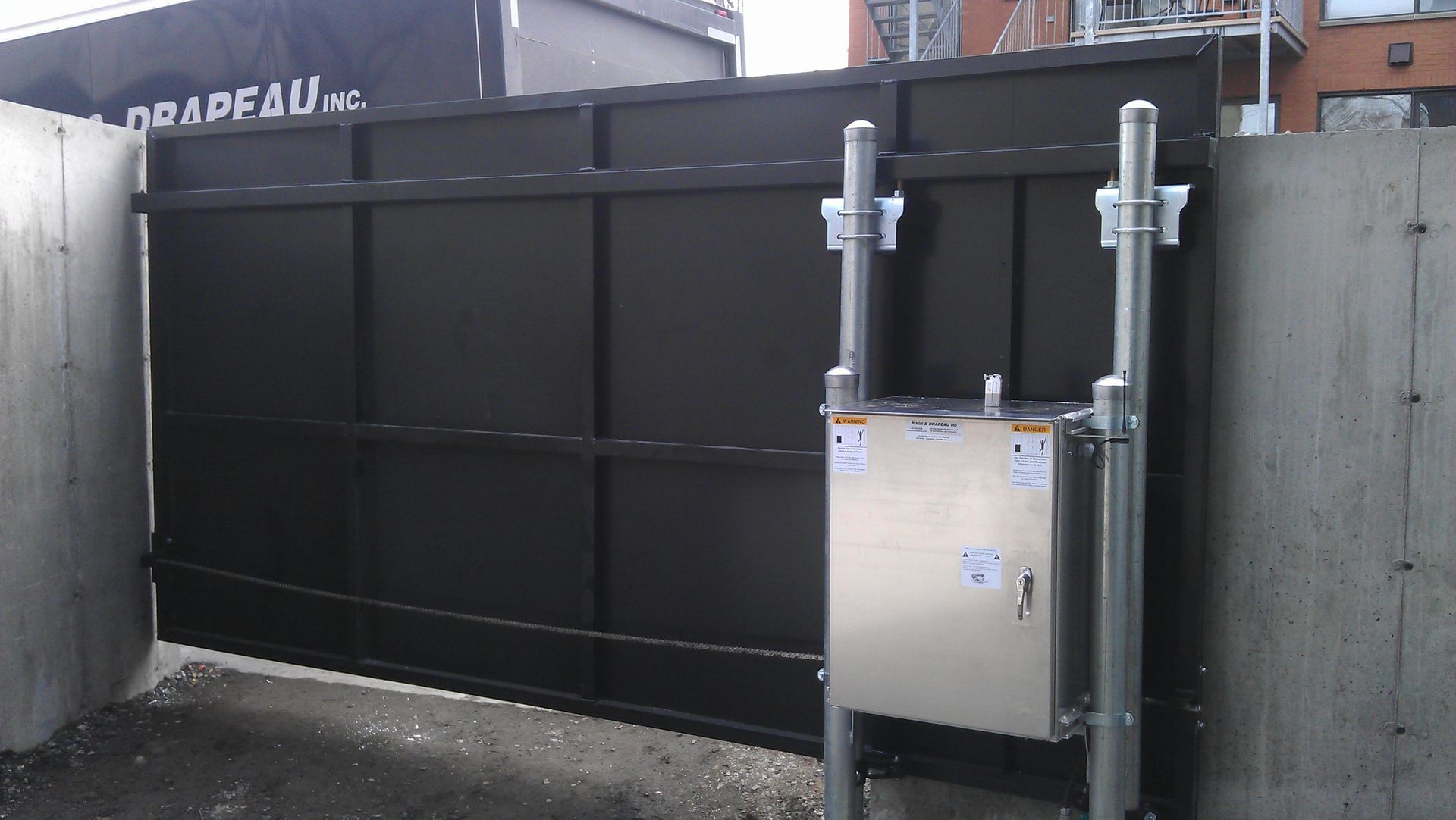 Un portail coulissant avec un boîtier en acier inoxydable en dessous