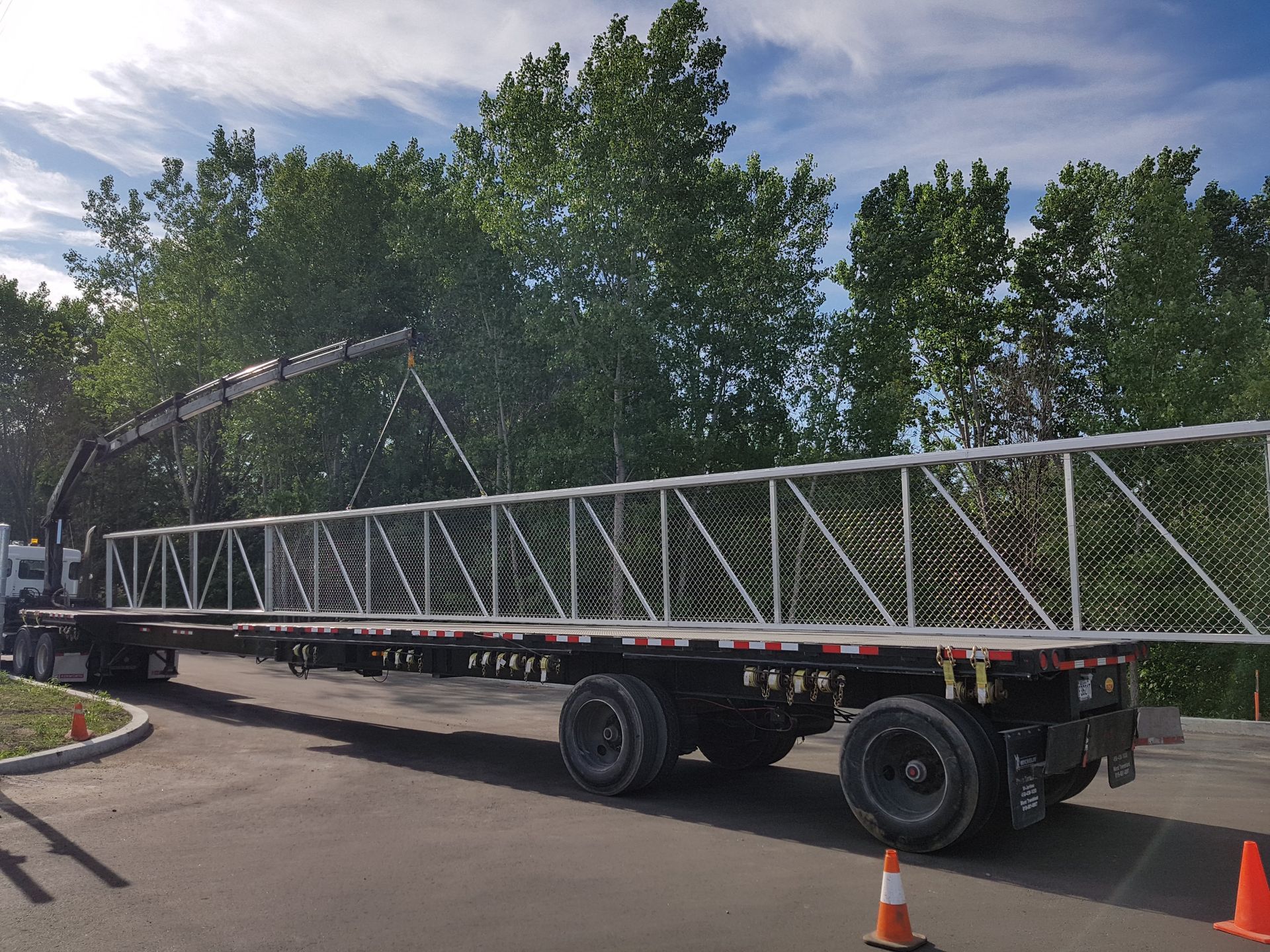 Une grande remorque avec un pont dessus est garée sur le bord de la route.