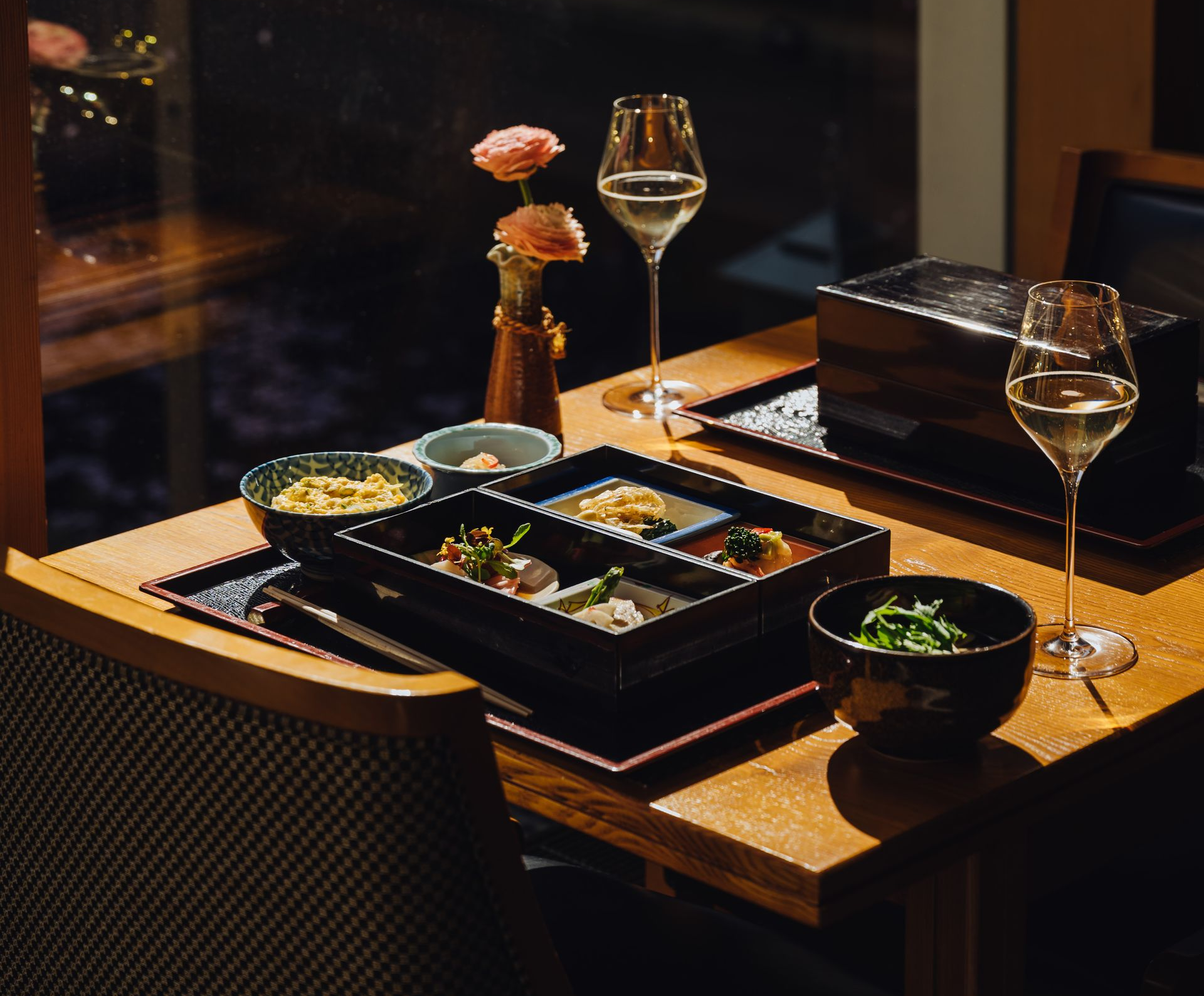 A person in a suit pouring liquid from a glass decanter into a small cup on a table.