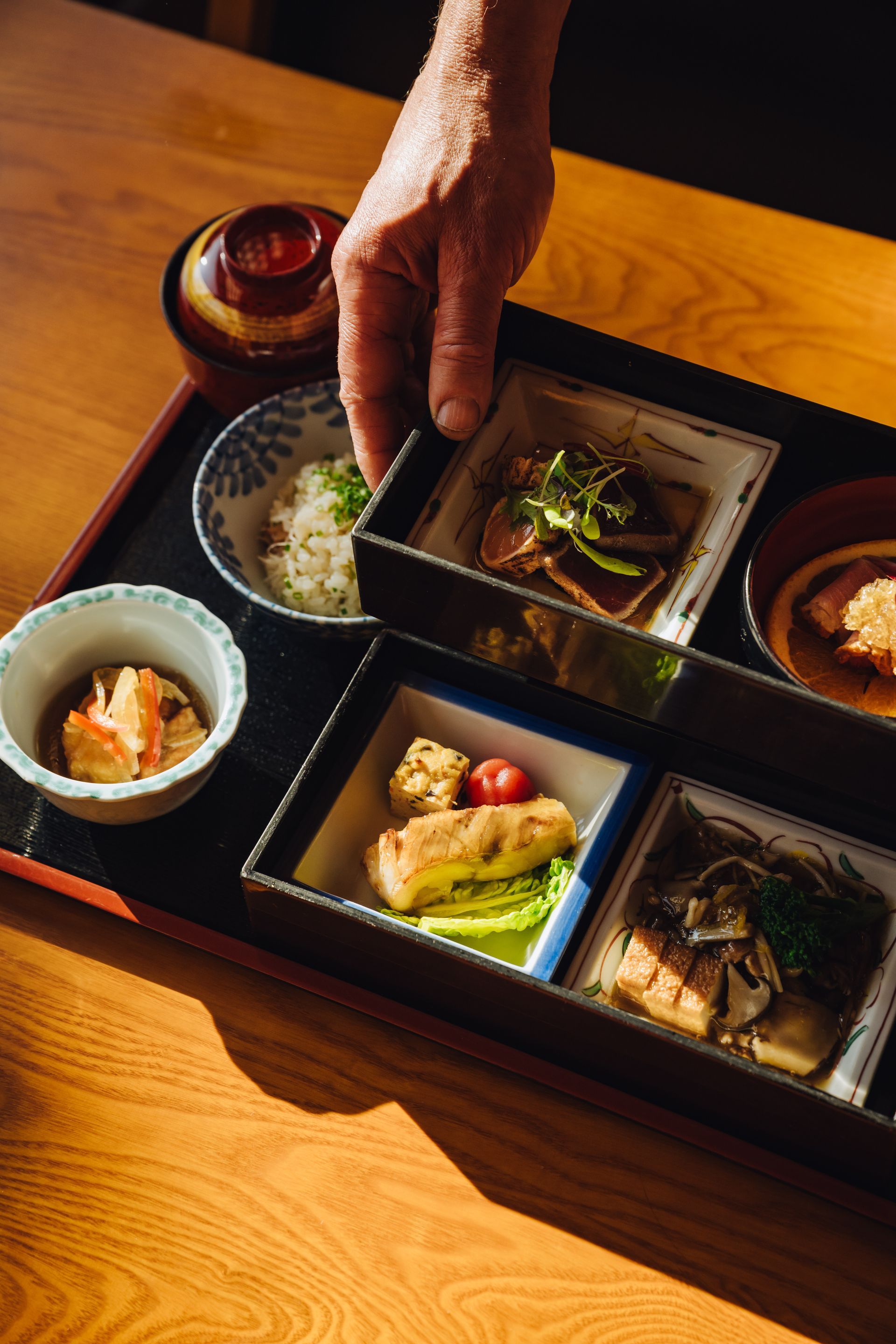 Japanese bento box with various colorful dishes including seafood, vegetables, and rice.