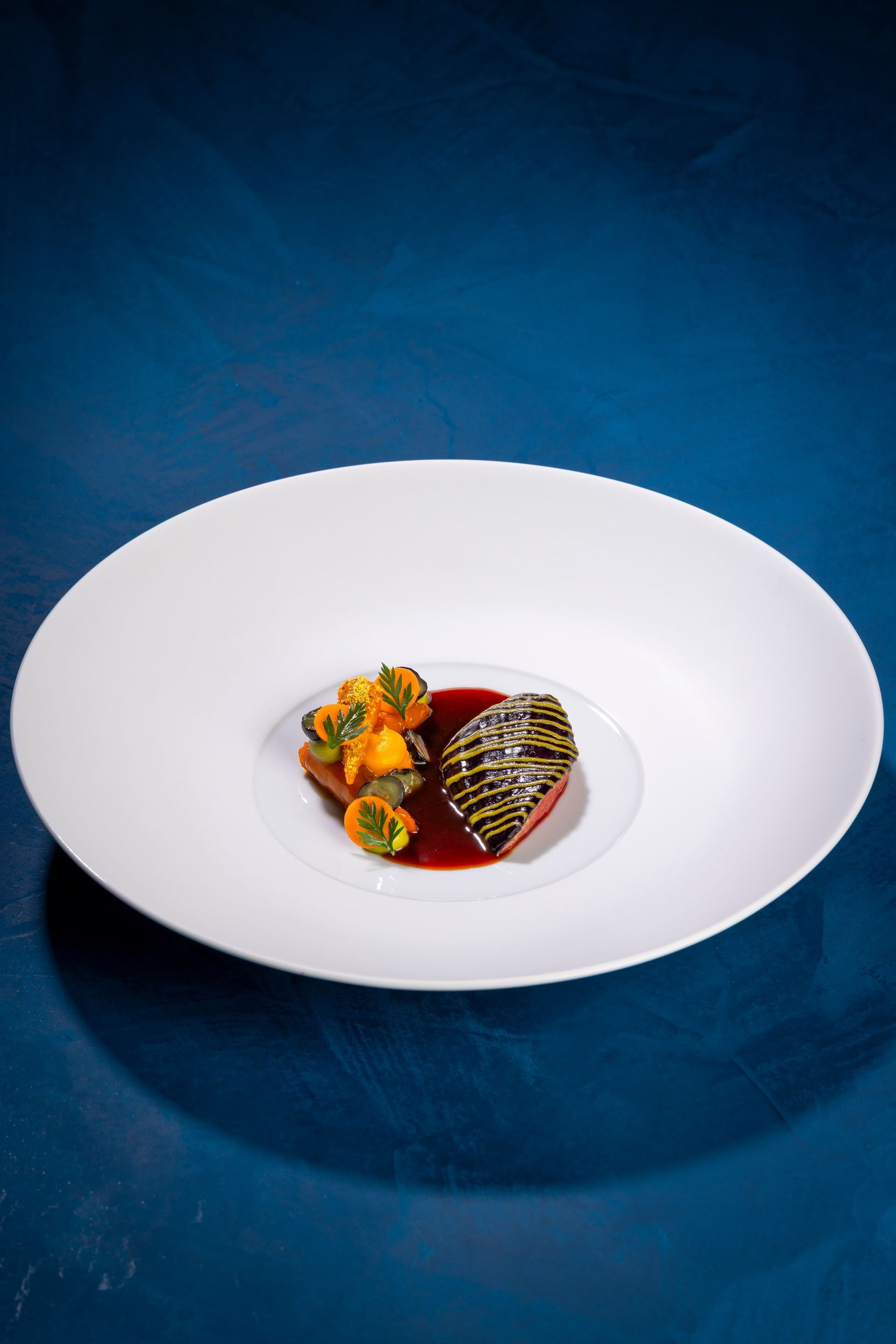 Waiter serving artfully plated food to a smiling diner in a fine dining restaurant.