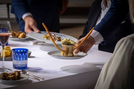 Restaurant table set with city view: tall buildings, blue glassware, and a white tablecloth.