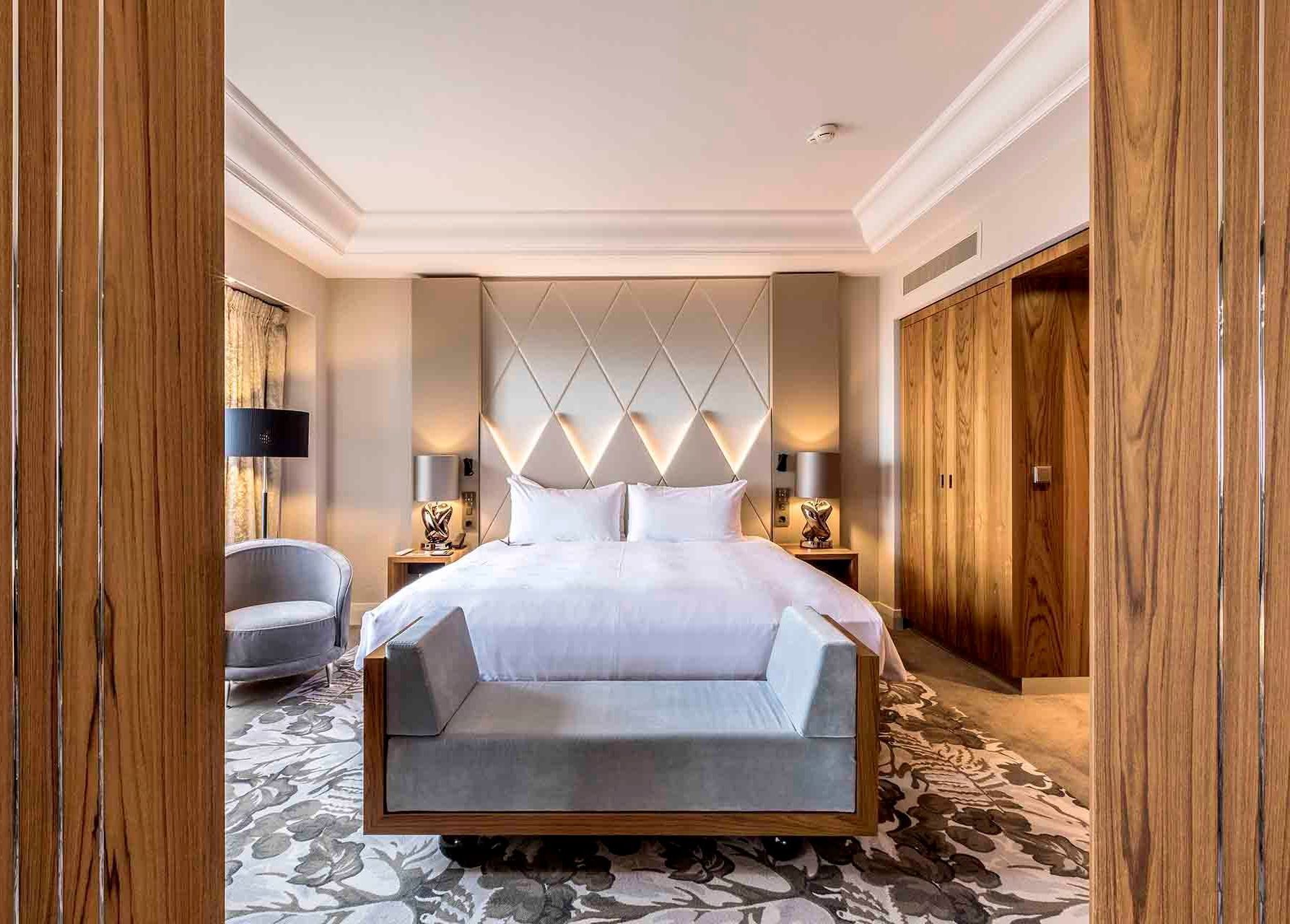 Bedroom with bed, bench, patterned rug, wood accents, and built-in closet.