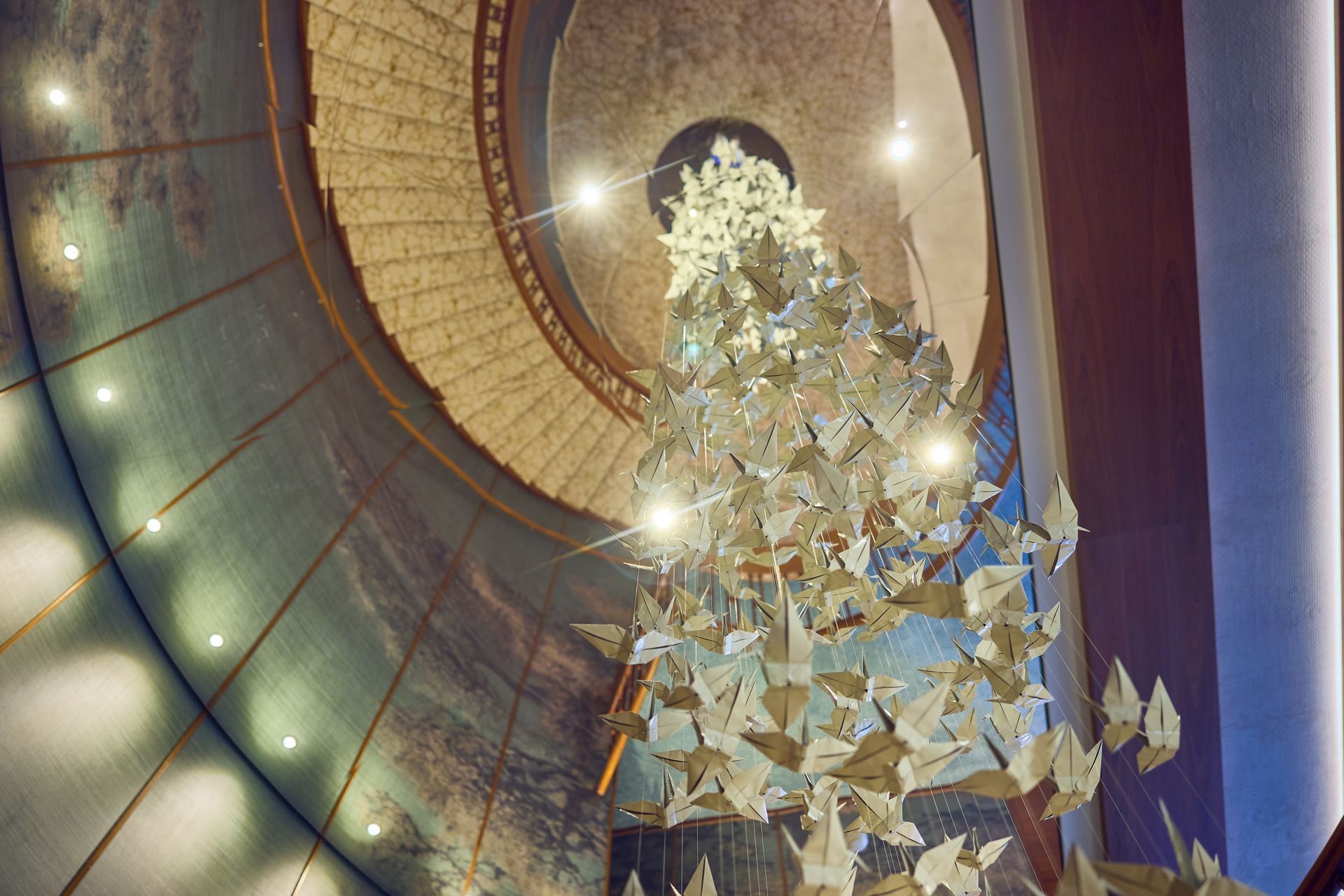 View upward of a spiral staircase with a paper butterfly installation. Soft lighting and muted colors.