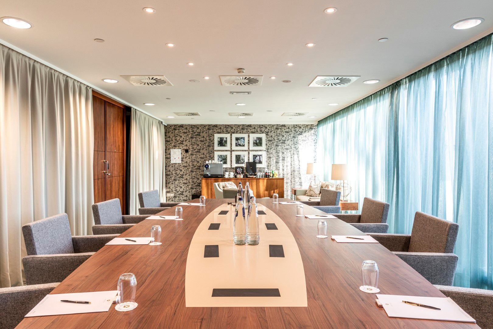 Conference room with long wooden table, chairs, and windows.