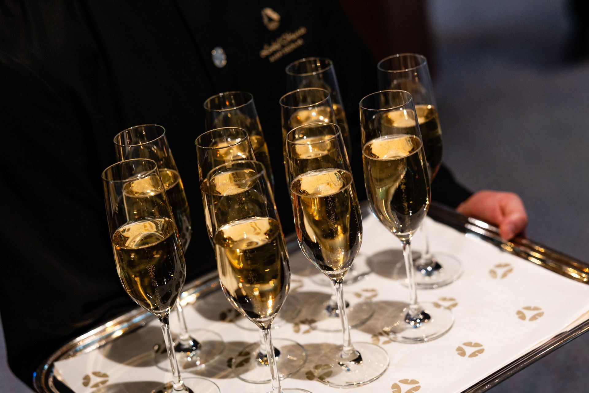 Tray of champagne flutes held by a person in a black shirt.