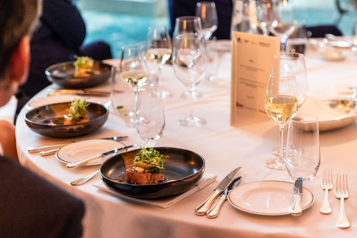 Formal dining table set with food, wine glasses, and silverware.