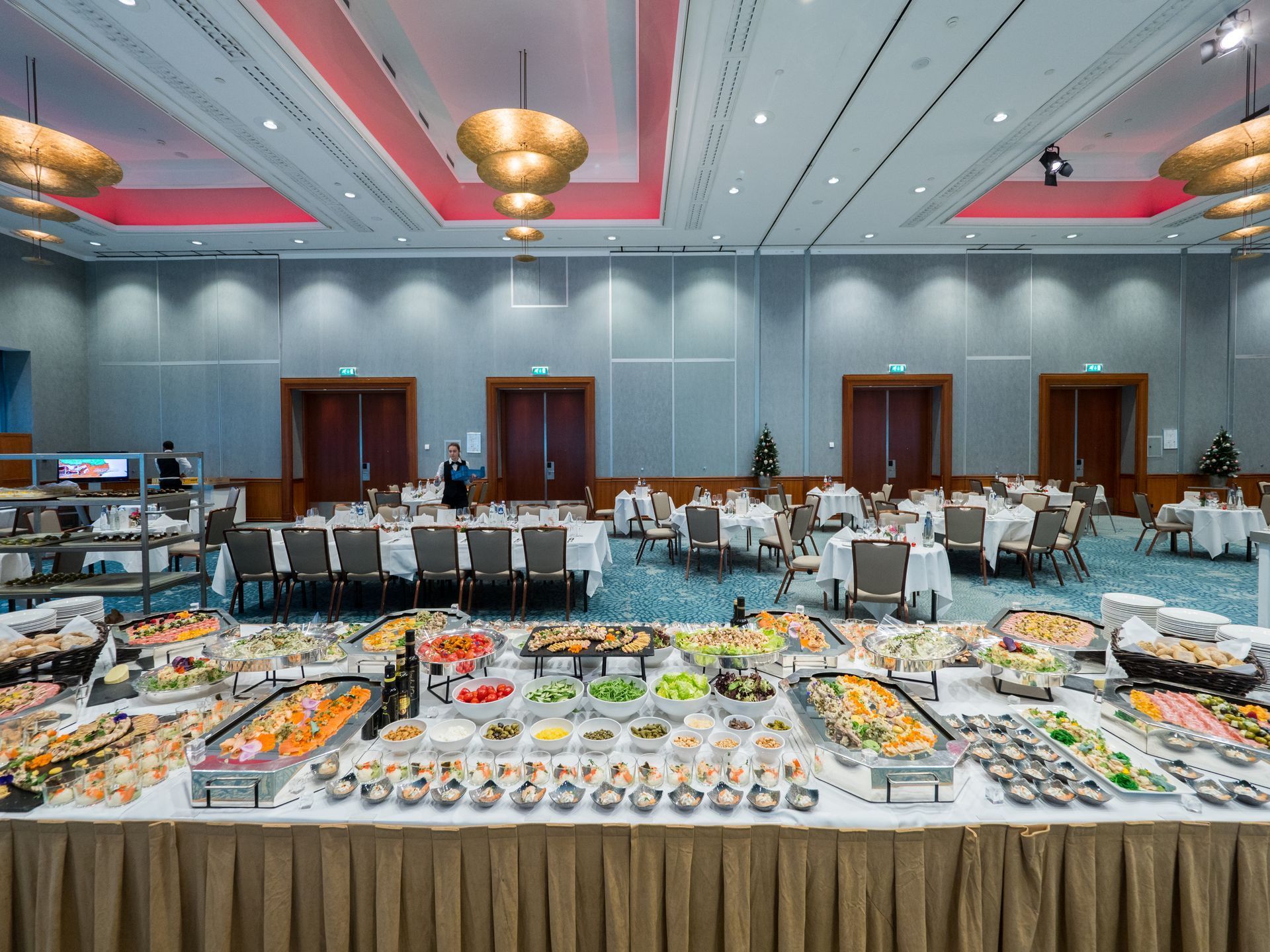 Buffet setup in a large ballroom with tables, food displays, and decorations.