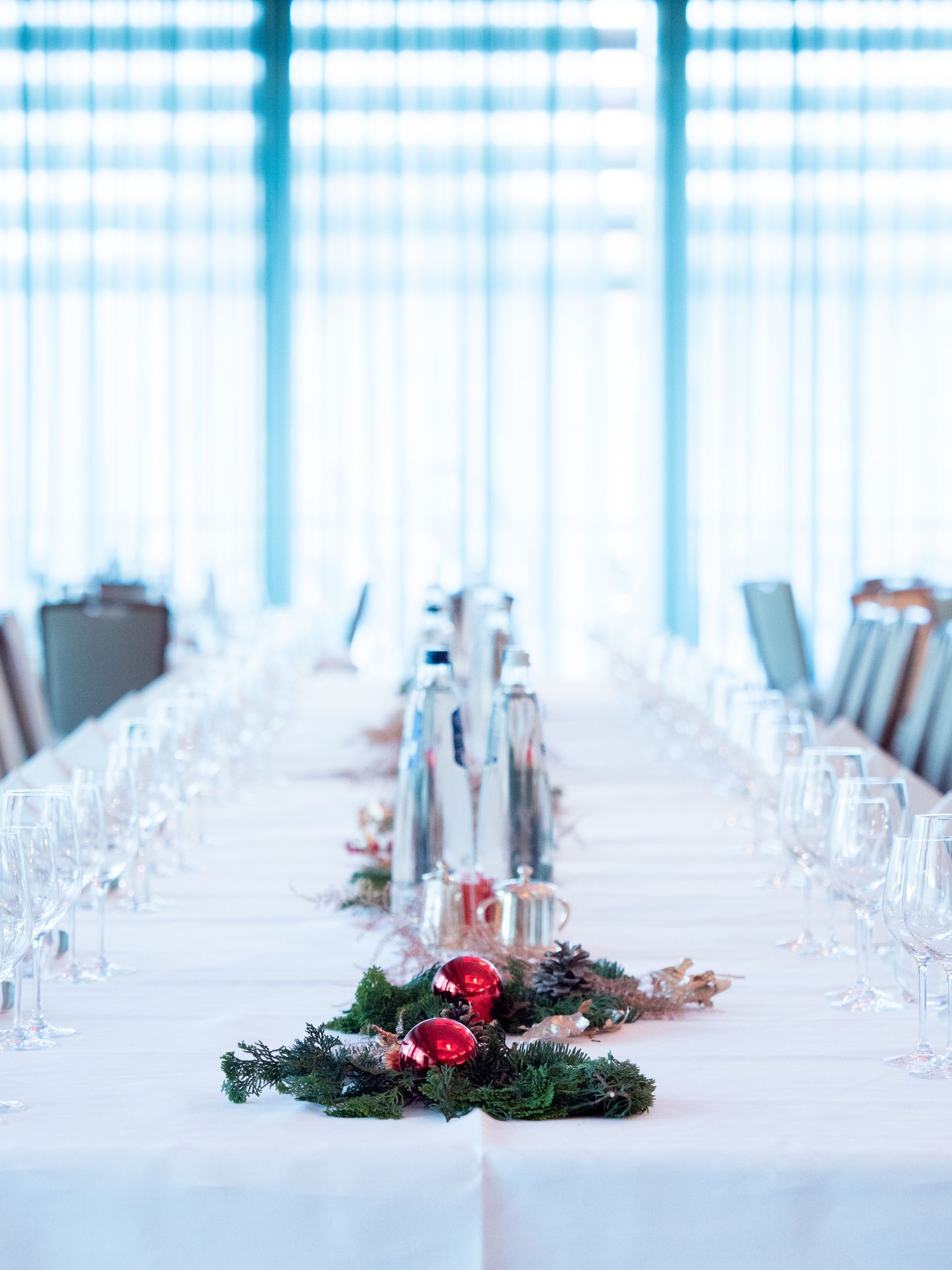 Long table set for a formal event, with glassware, water bottles, and a festive centerpiece.