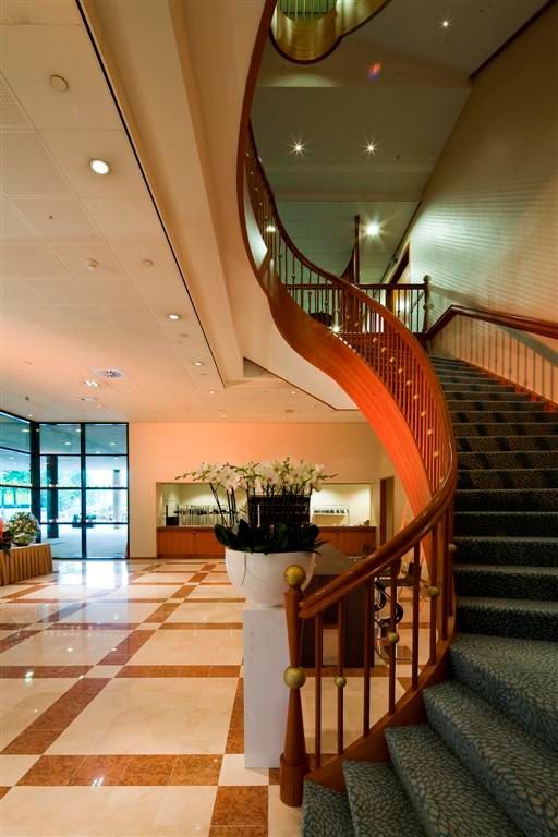 Elegant foyer with a curving wooden staircase and checkered floor.